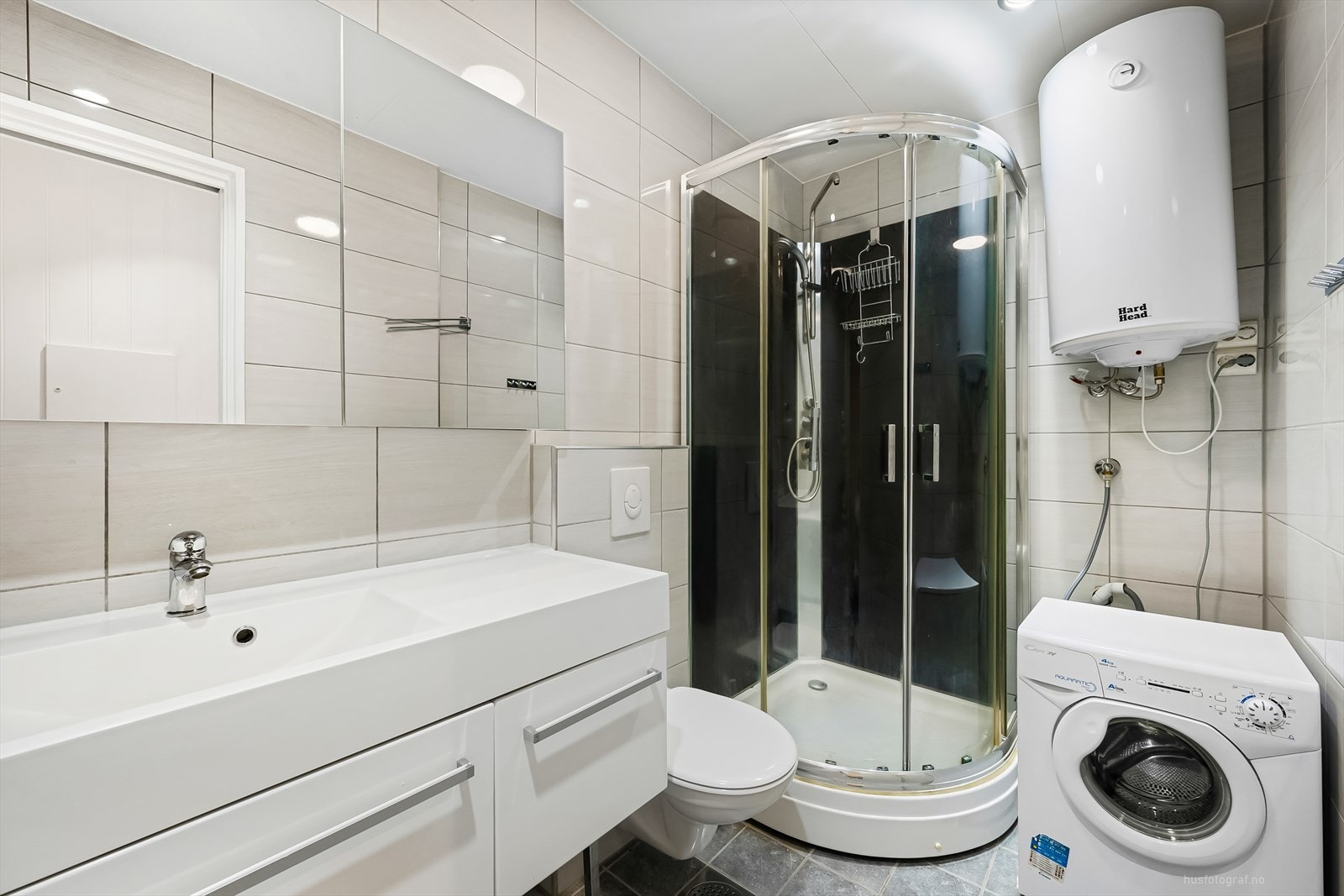 I garasjen er det innredet et bad med toalett, dusjkabinett, servant og opplegg for vaskemaskin. Galleribilde