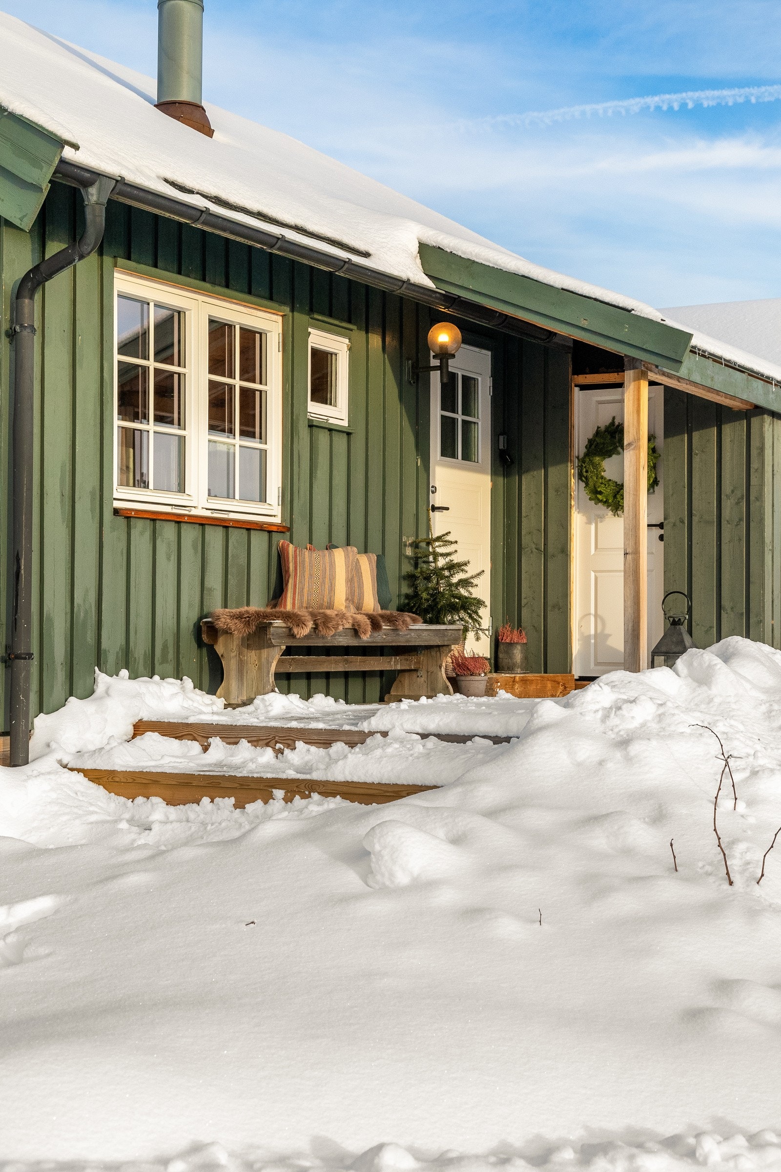 Hytten har et pent, overbygd inngangsparti med veggmontert utebelysning. Galleribilde