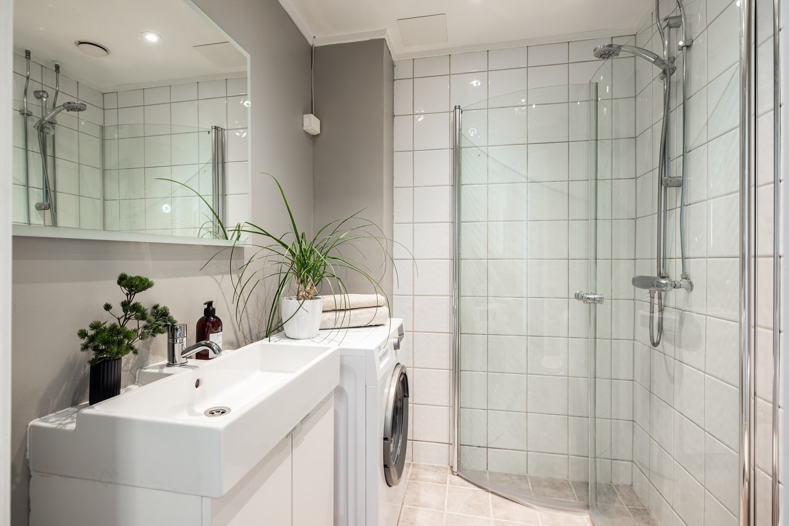 Lyst, flislagt bad med gulvvarme og opplegg for vaskemaskin Galleribilde