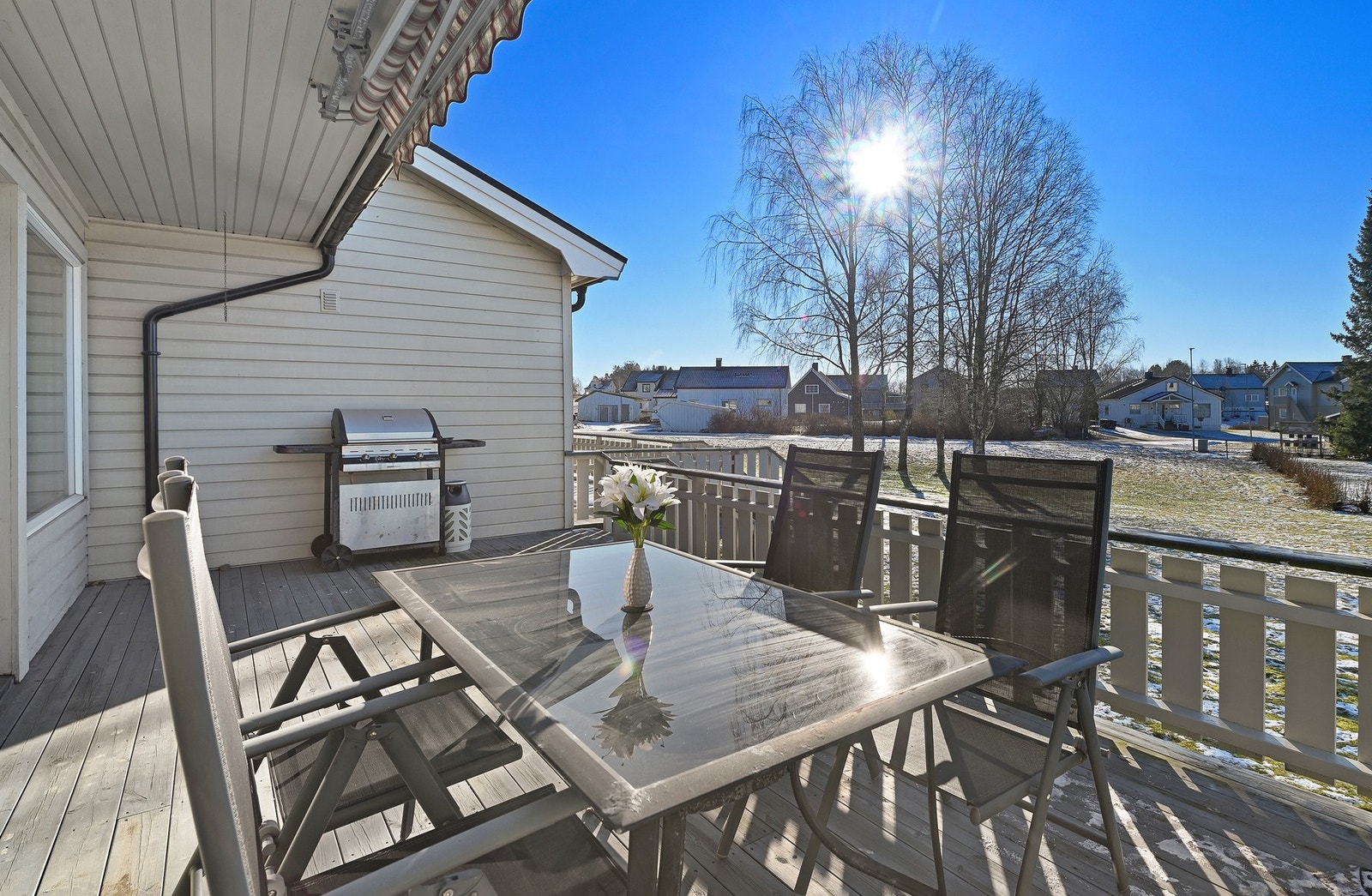 Stor terrasse med rekkverk og overbygg, som gir en fin utsikt over nabolaget og grønne områder. Galleribilde