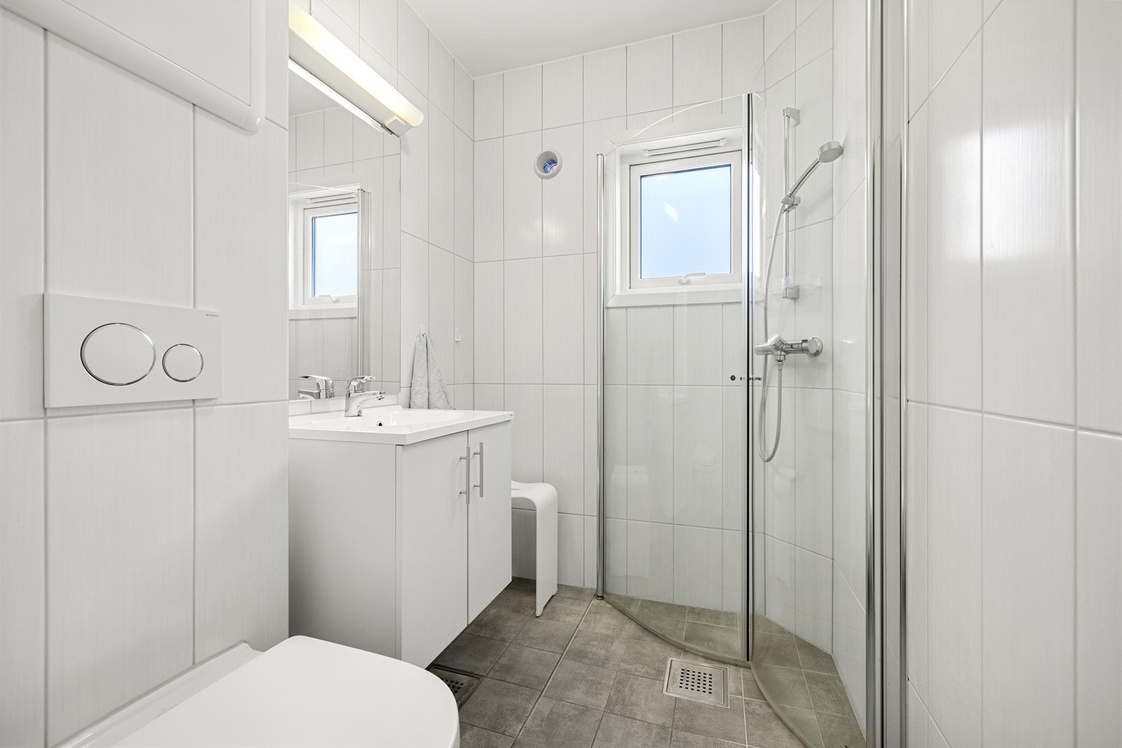 Pent flislagt baderom, pusset opp i 2017. Badet er utstyrt med vegghengt toalett, servant med skap og dusjnisje med glassdører. Galleribilde