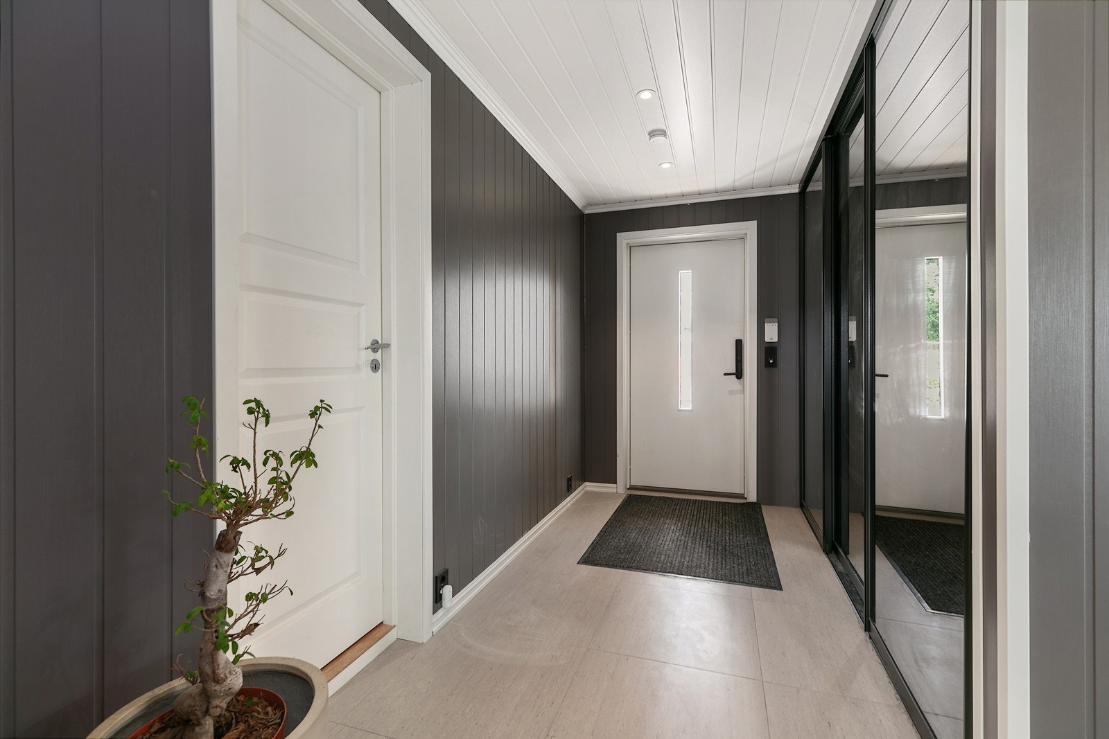 Velkommen inn! Entreen har et stilrent, flislagt gulv som bærer med seg et praktisk preg. Det er god plass til oppheng for yttertøy , i skyvedørsgarderobe noe som gjør det enkelt å holde orden i inngangspartiet. Galleribilde