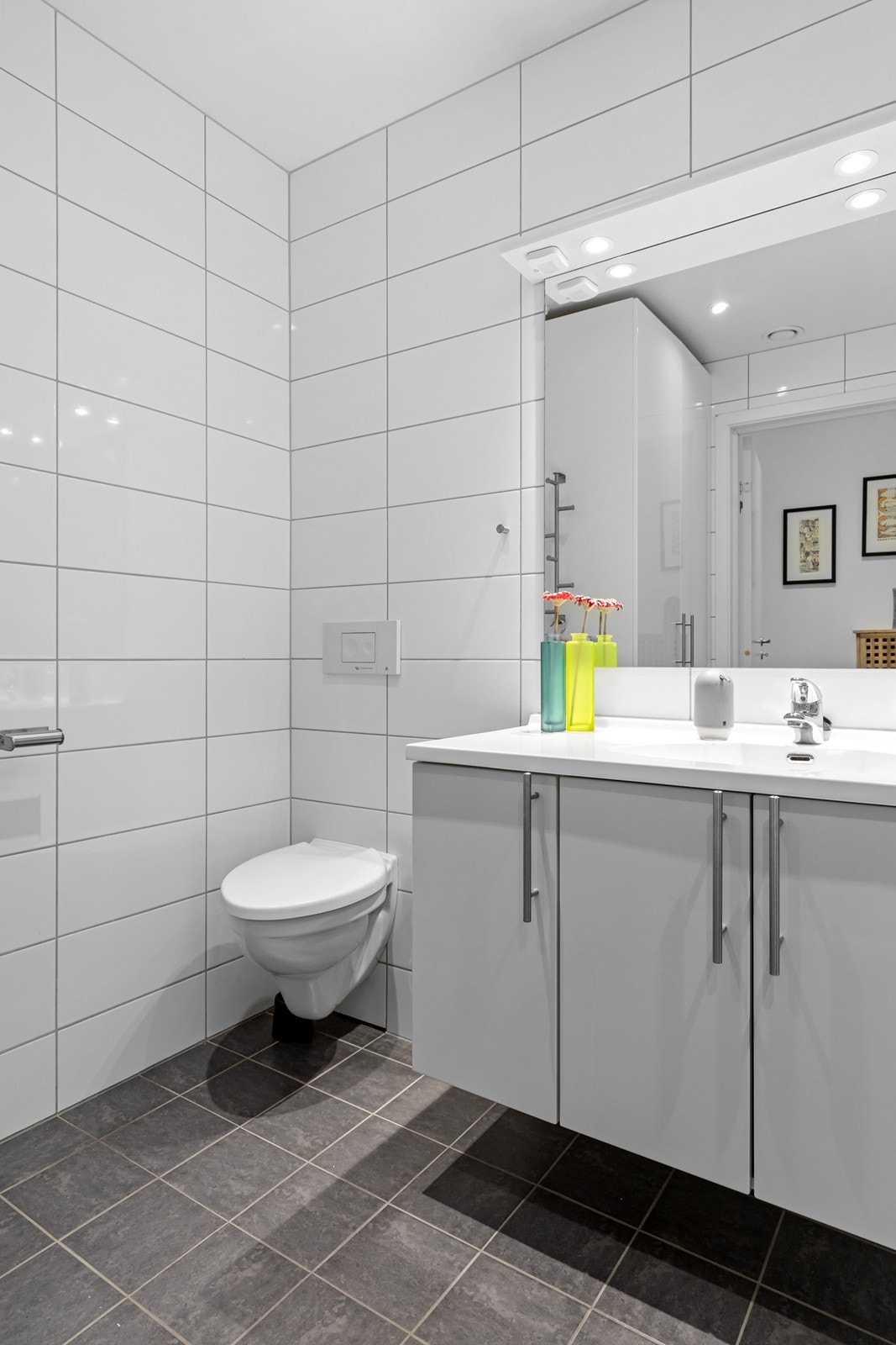 Badet er innredet med vegghengt toalett, dusjkabinett og servant med skapinnredning. Galleribilde