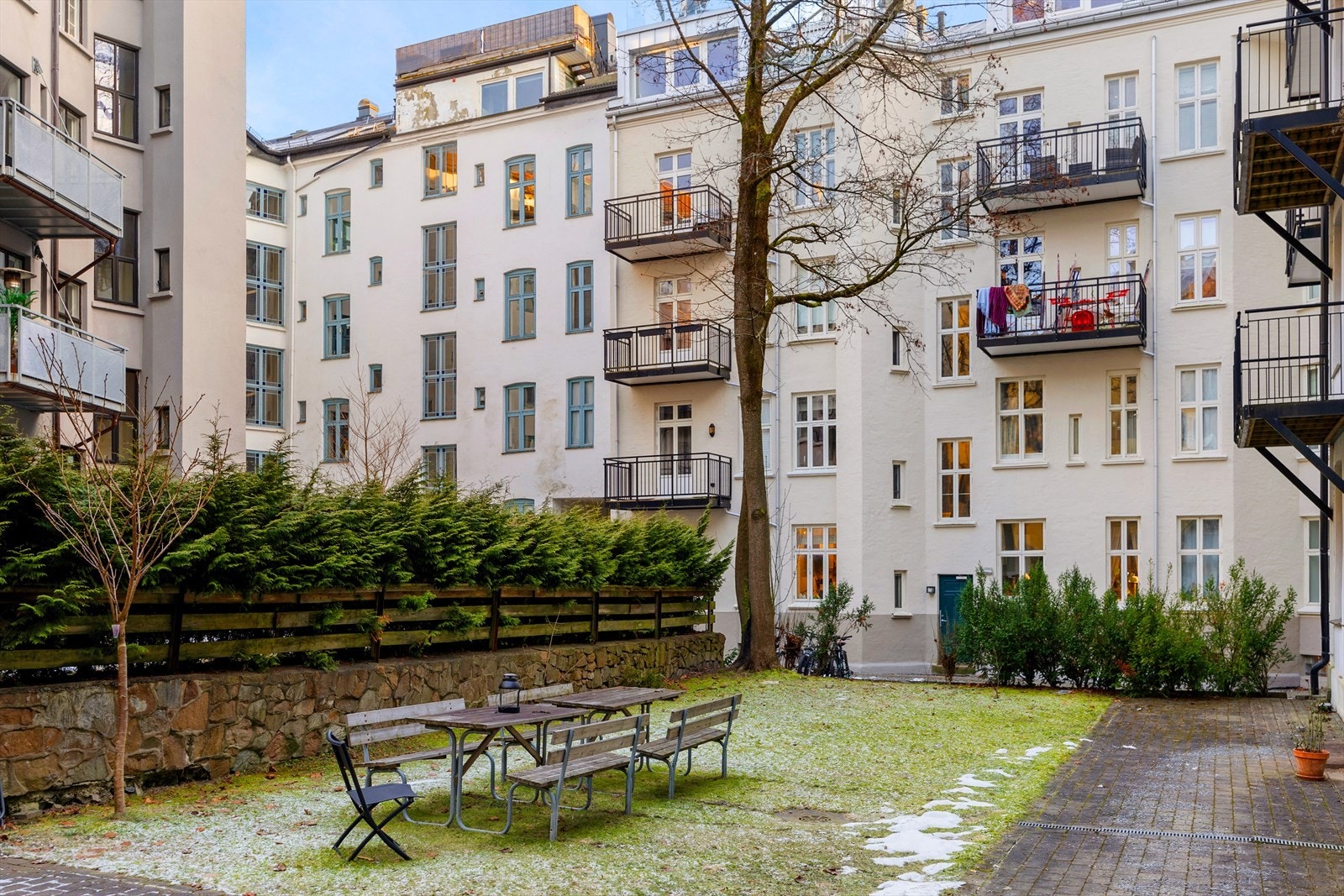 Pent opparbeidede uteområder med sitterupper og plen i bakgård. Galleribilde