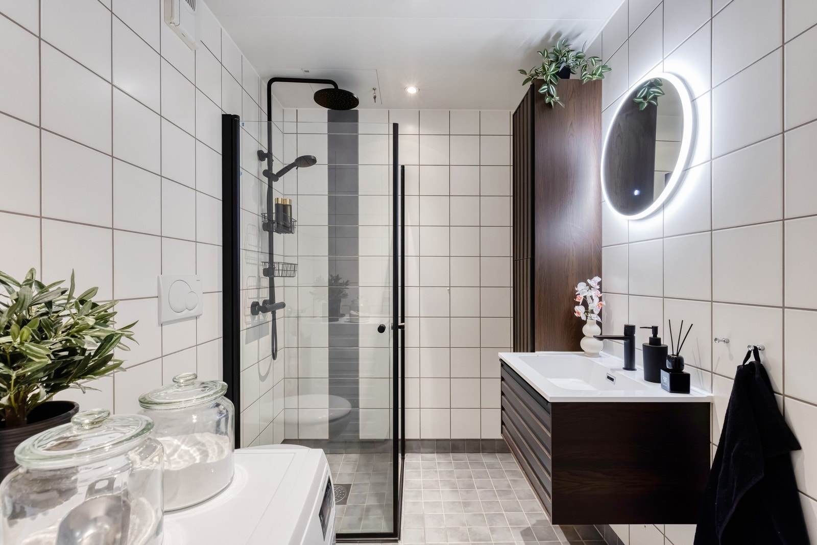 Badet er tidløst innredet med lekkert møblement og lyse fliser på gulv og vegger Galleribilde