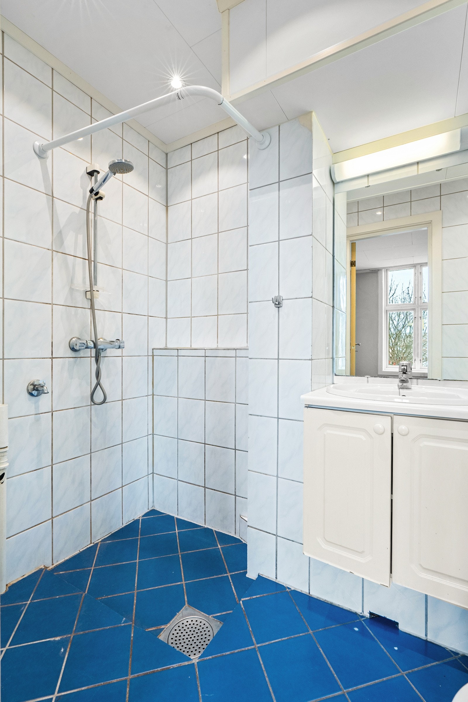 Badet er av eldre dato. Overflater er flislagt og det er varmekabler med termostat i badegulvet. Opplegg for vaskemaskin til venstre i bildet. Galleribilde