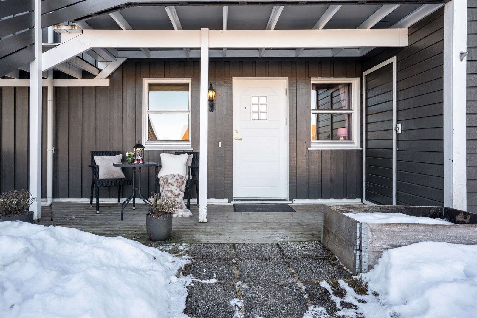 Leiligheten har et stort, overbygd inngangsparti - perfekt å plassere et kafé-sett for morgenkaffen. På høyre side er en romslig sportsbod plassert. Galleribilde