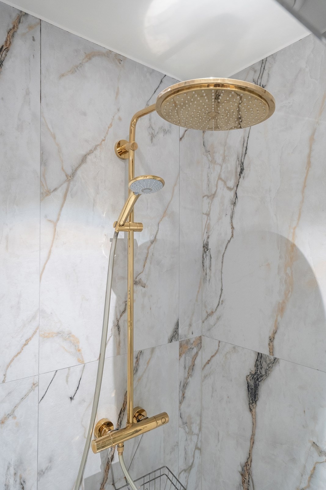 Stilfullt regnfallsarmatur og pene fliser preger badet. Galleribilde