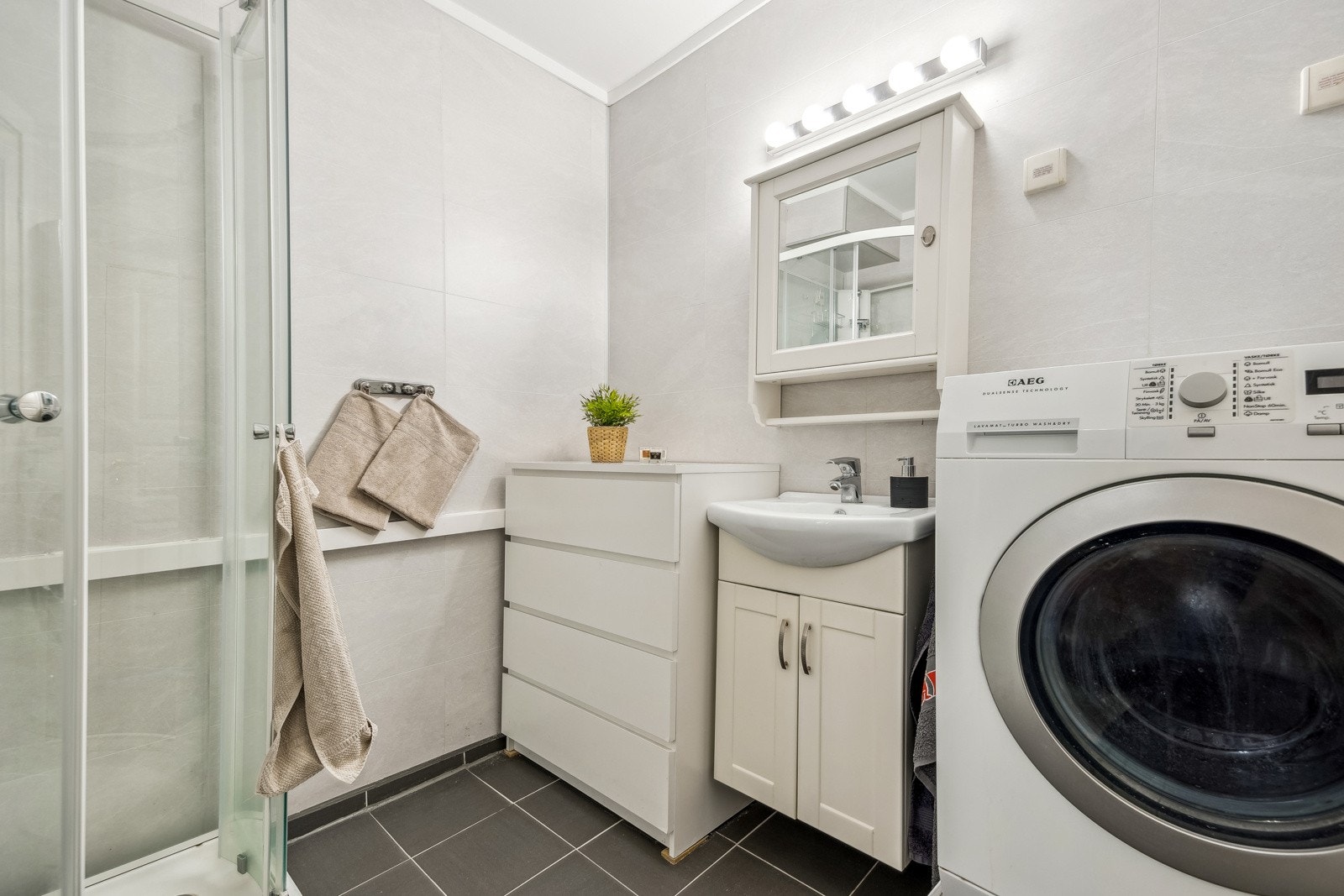 Leilighetens lyse baderom er målt til 5 kvm og har flislagt gulv og våtromsplater på vegg. Galleribilde