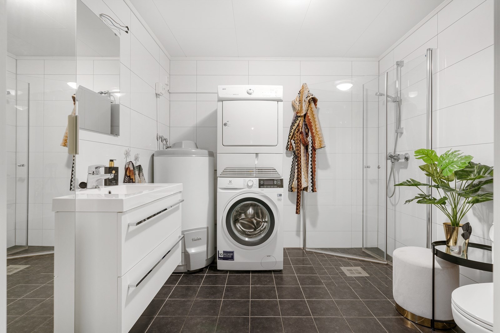 Nydelig flislagt bad fra byggeåret med blant annet vegghengt toalett, dusjhjørne med glassdører, gulvvarme og opplegg til vaskemaskin. Galleribilde