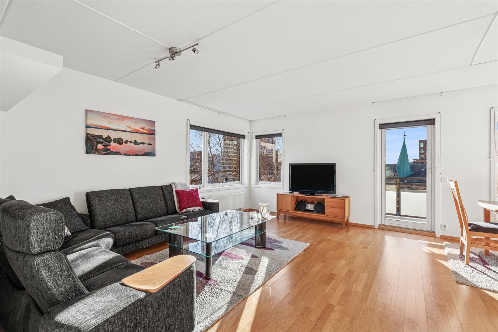 Lys og romslig stue lys fra tre sider. Hvitmalte vegger og store vinduer som slipper inn rikelig med dagslys. Galleribilde