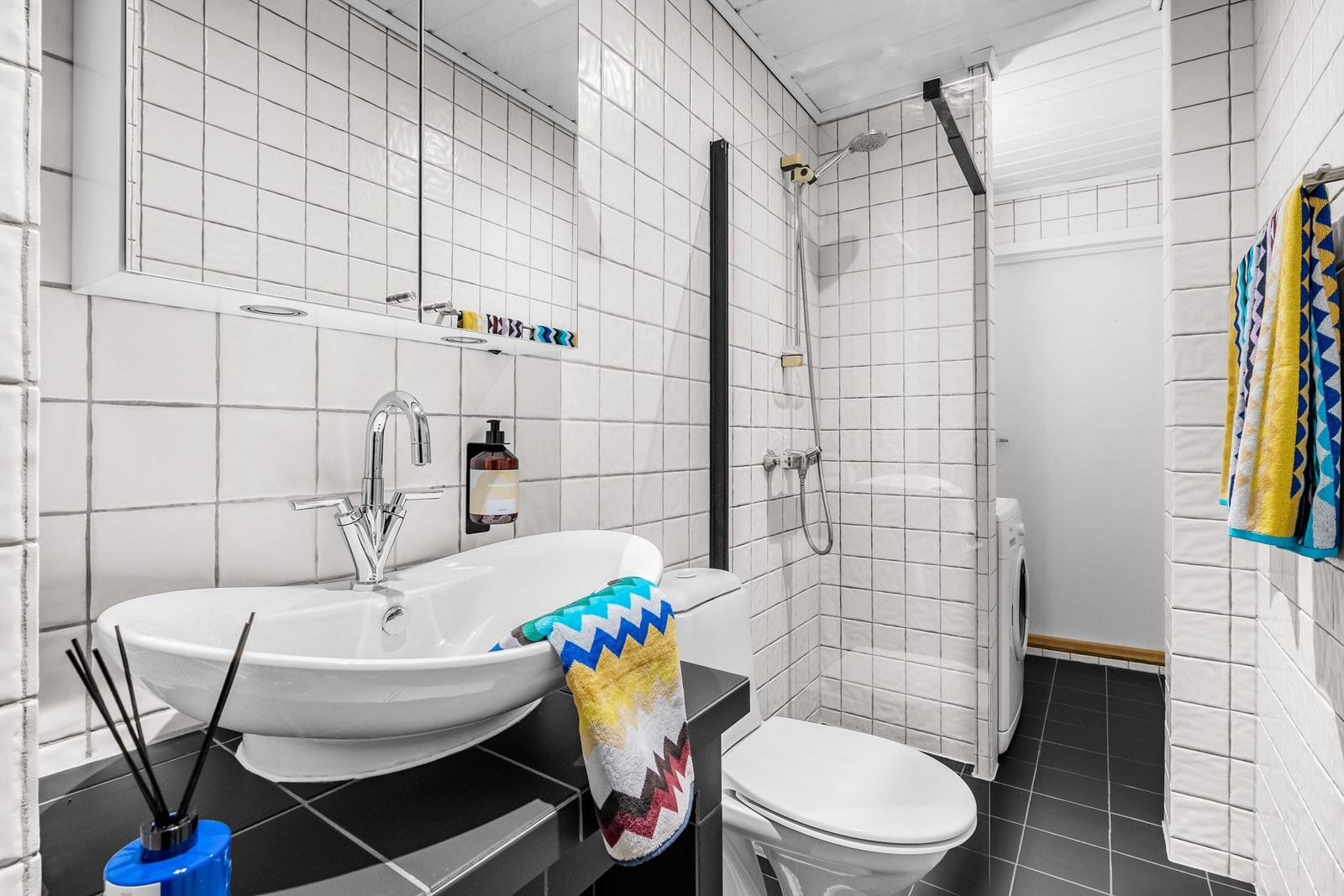 Helt og fint bad med flislagt gulv med gulvvarme og flislagte vegger. Det er nedsenket himling av panel med downlights, samt gulvstående servant med ett-greps armatur. Galleribilde