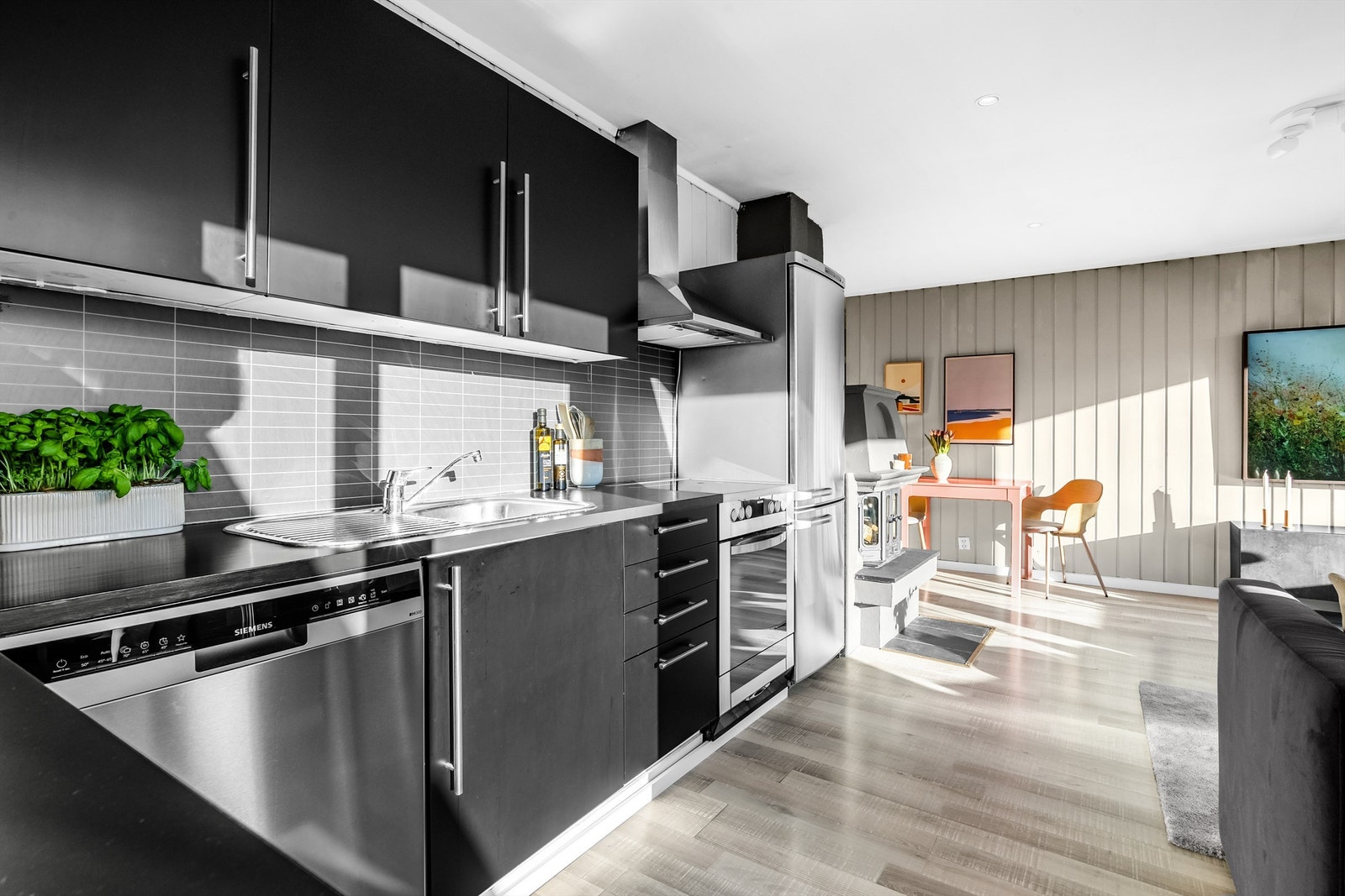 Stilren kjøkkeninnredning med mørke fronter og malt benkeplate.
Frittstående komfyr, kjøl/frys, vinskap, samt oppvaskmaskin. Galleribilde