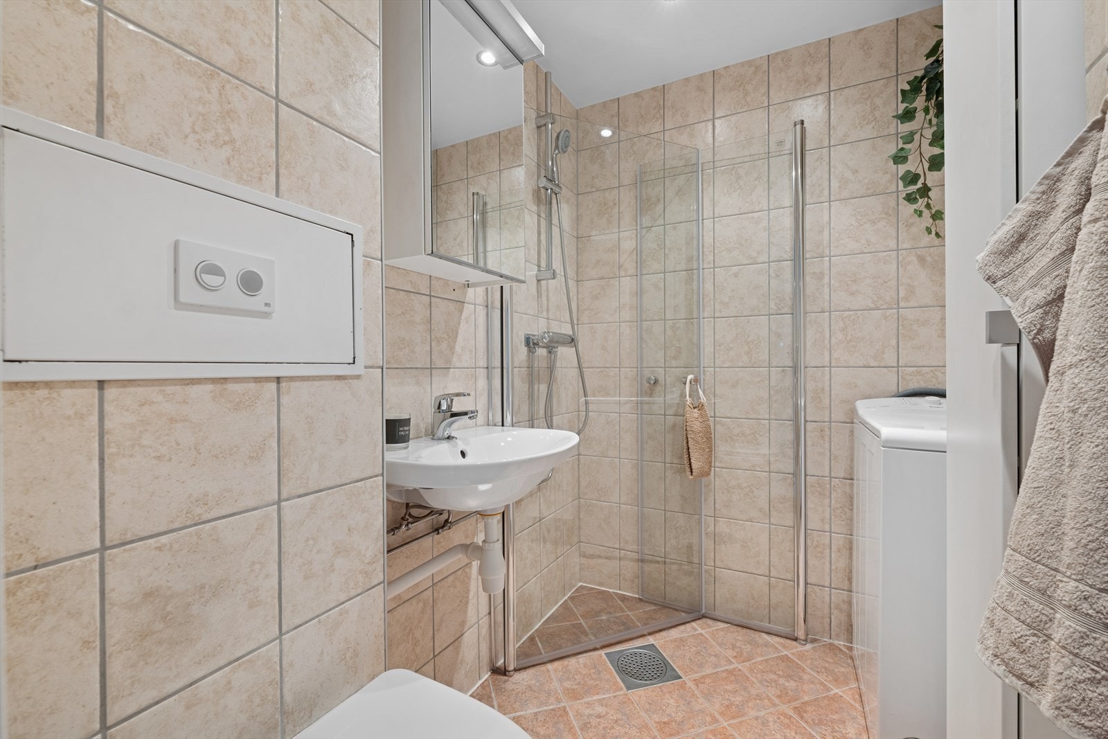 Baderommet er utstyrt med dusjhjørne, vegghengt toalett, servant og opplegg til vaskemaskin. Galleribilde