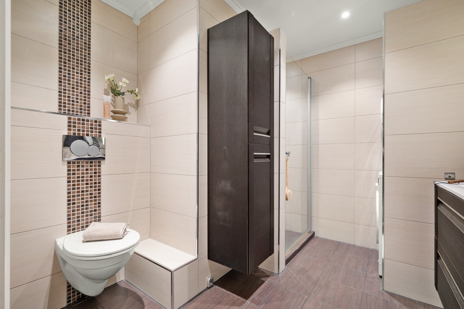 Badet er utstyrt med toalett, servant, dusjdører i klart glass og opplegg for vaskemaskin. Galleribilde