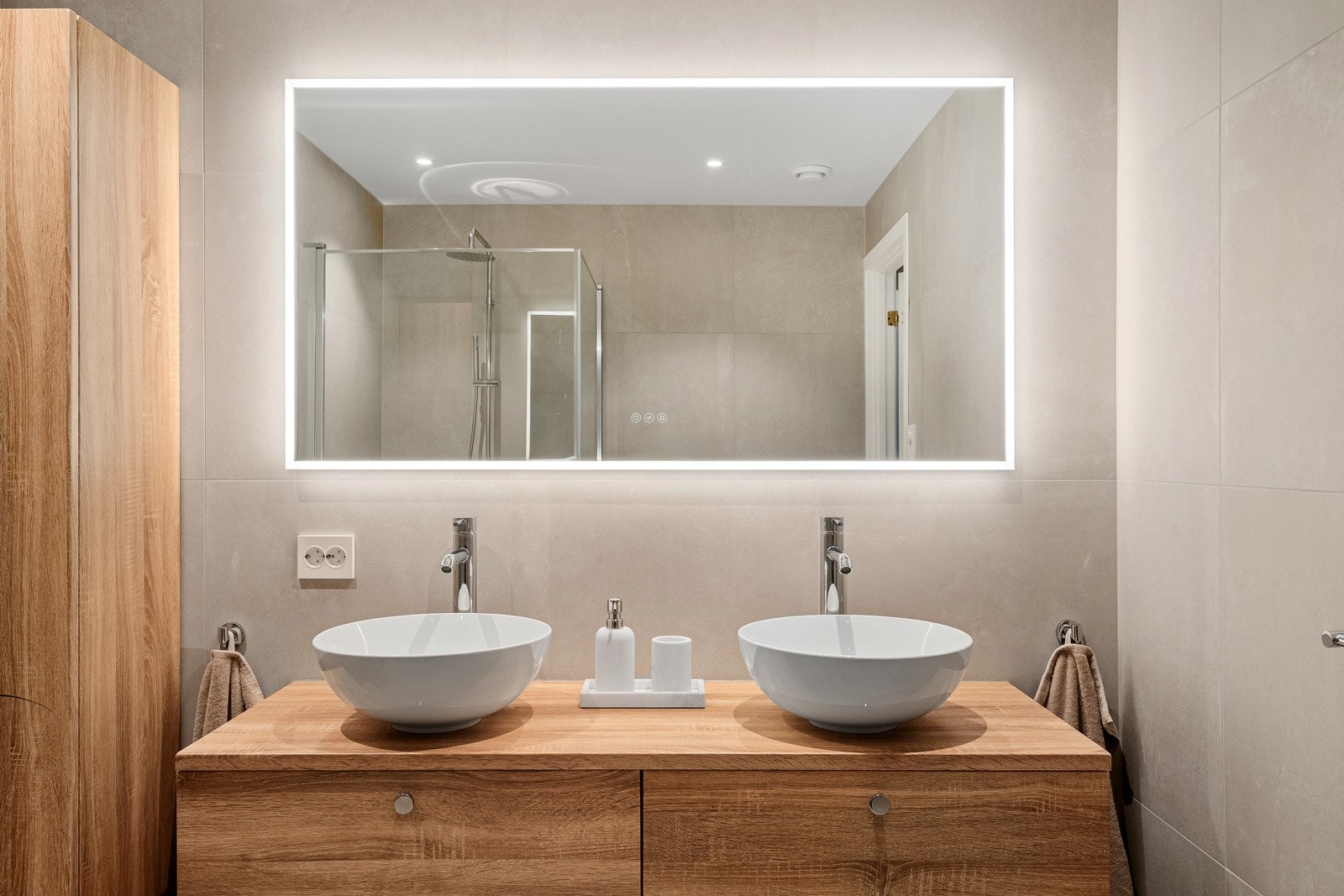 Utstyrt med dusjhjørne med glassdører, dobbel servant og stort speil med integrert belysning. Galleribilde