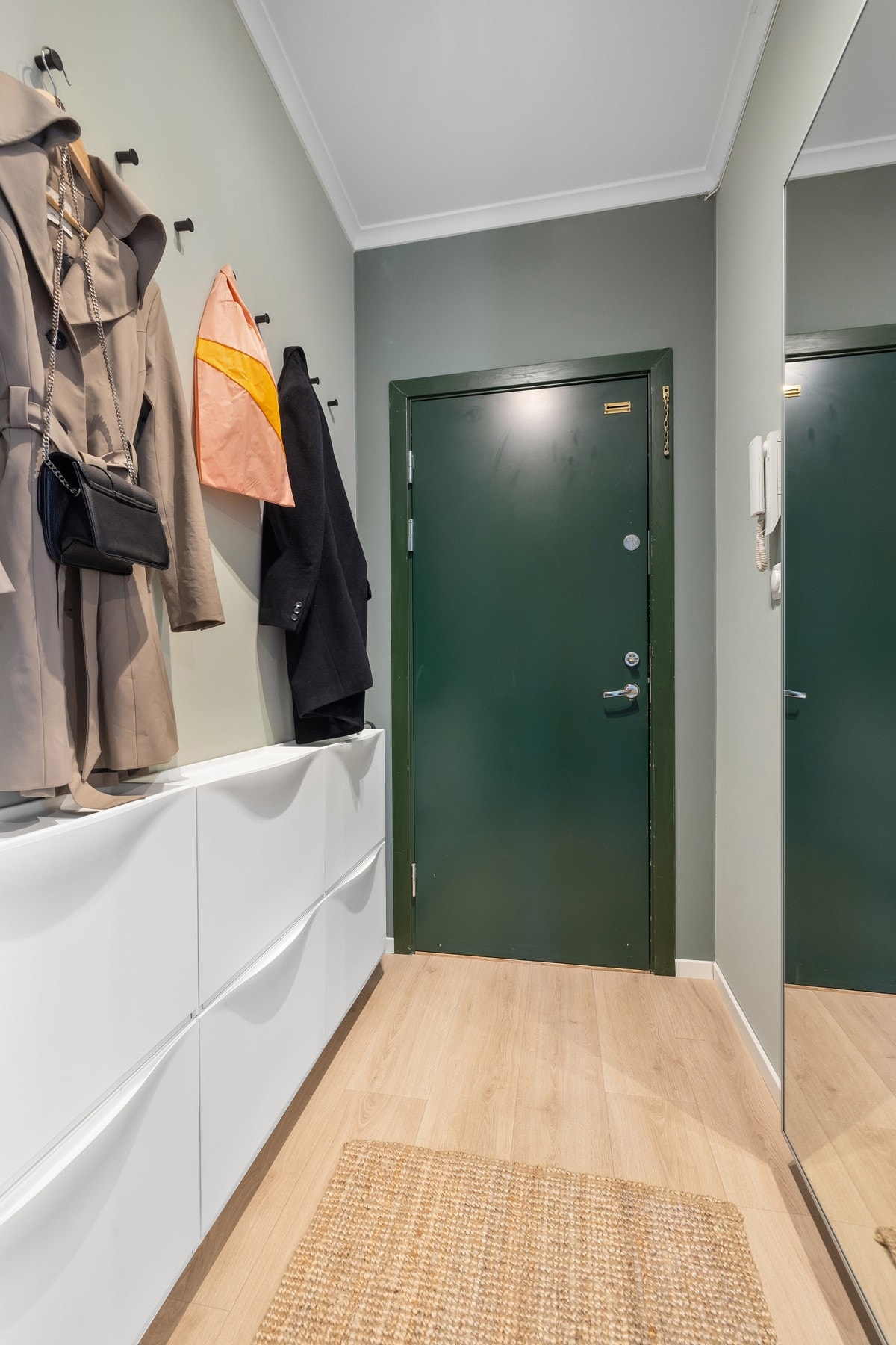 Romslig entre med god plass til å henge opp jakker samt sette fra seg sko i veggmonterte skohyller Galleribilde