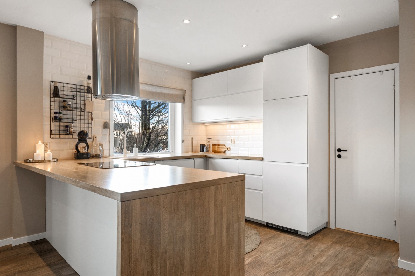 Lekkert kjøkken som holder et tidløst preg med sine lyse overflater og integrerte hvitevarer Galleribilde