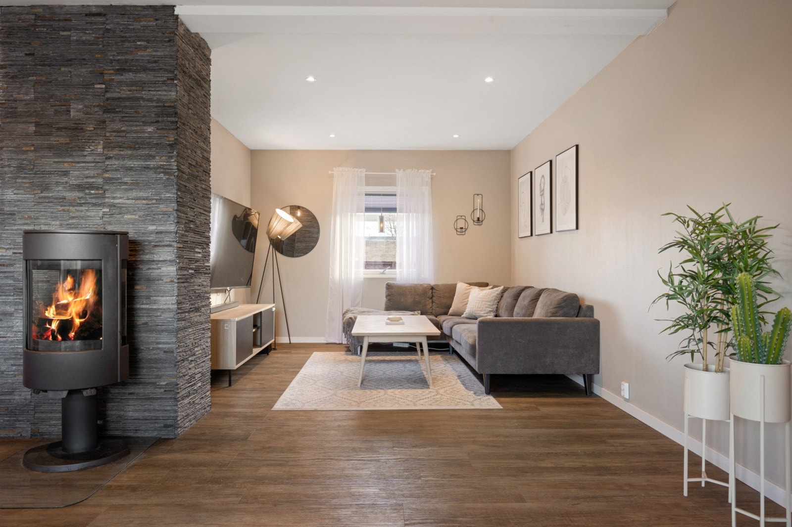 En lys og romslig stue som får godt med naturlig lys inn fra store vindusflater Galleribilde