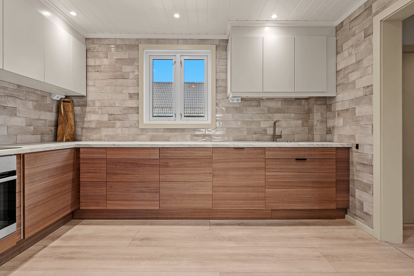 Kjøkkeninnredningen har mørke Edge Walnut fronter, mens overskapene har fronter i i Trend Warm White. Galleribilde