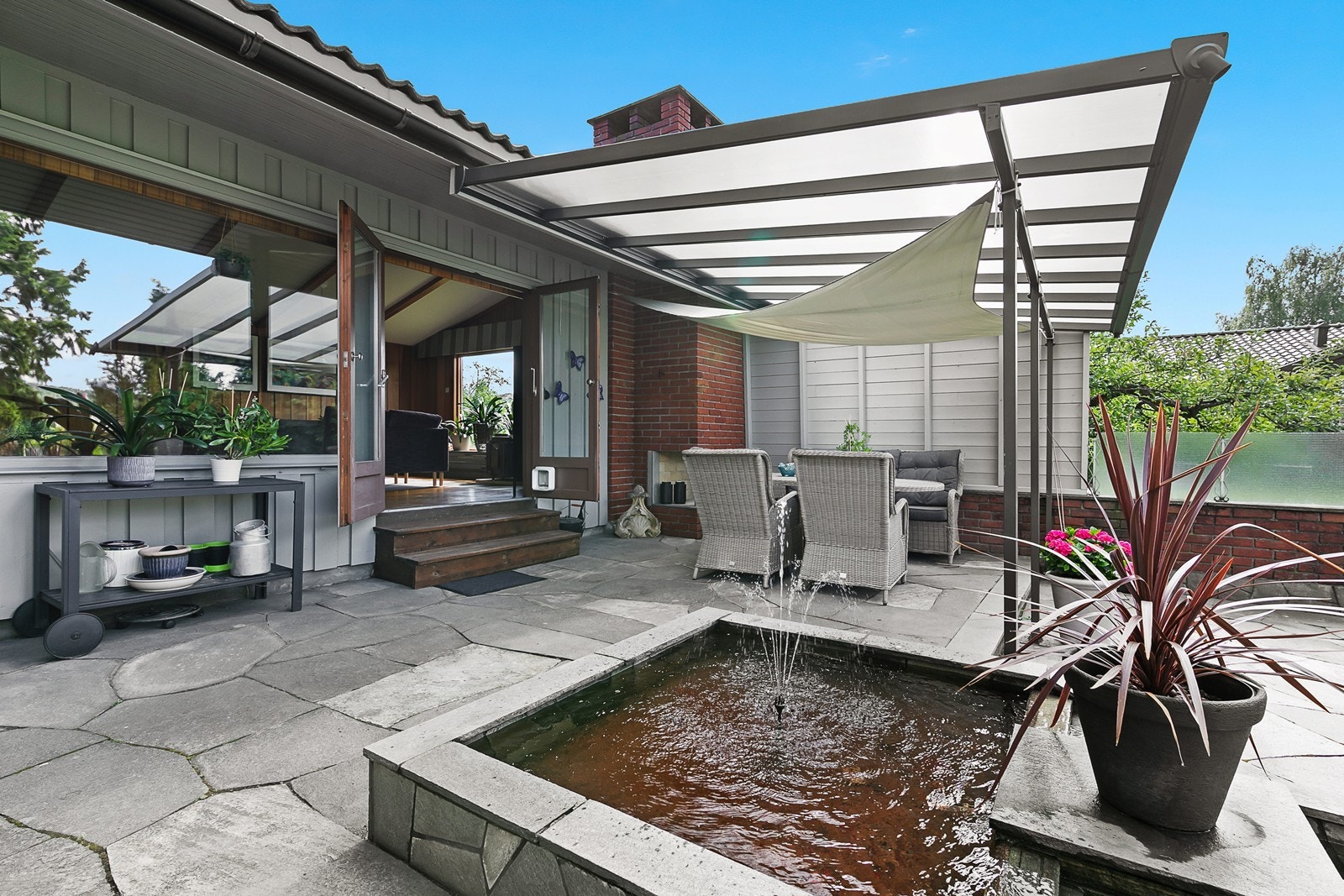 Terrassen er opparbeidet med bruddheller av skifer, og i hjørnet under den overbygde delen er det en koselig, murt peis. Galleribilde