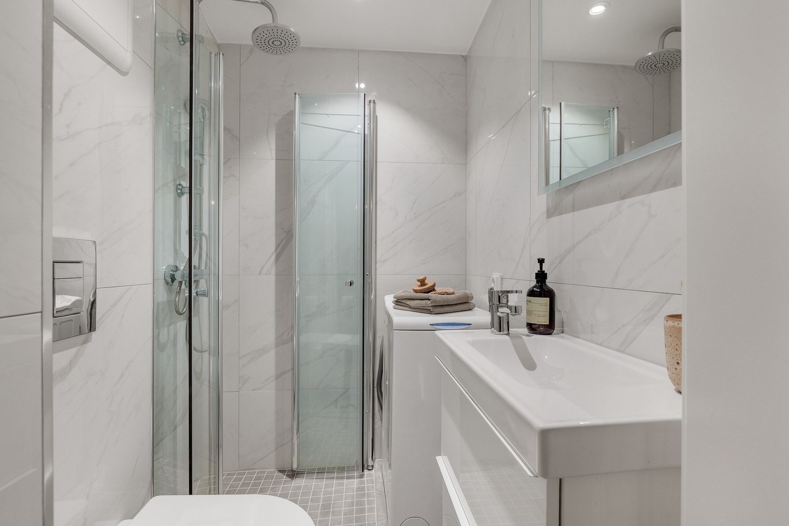 Innredet med vegghengt servant, samt vegghengte dusjdører i glass. Galleribilde