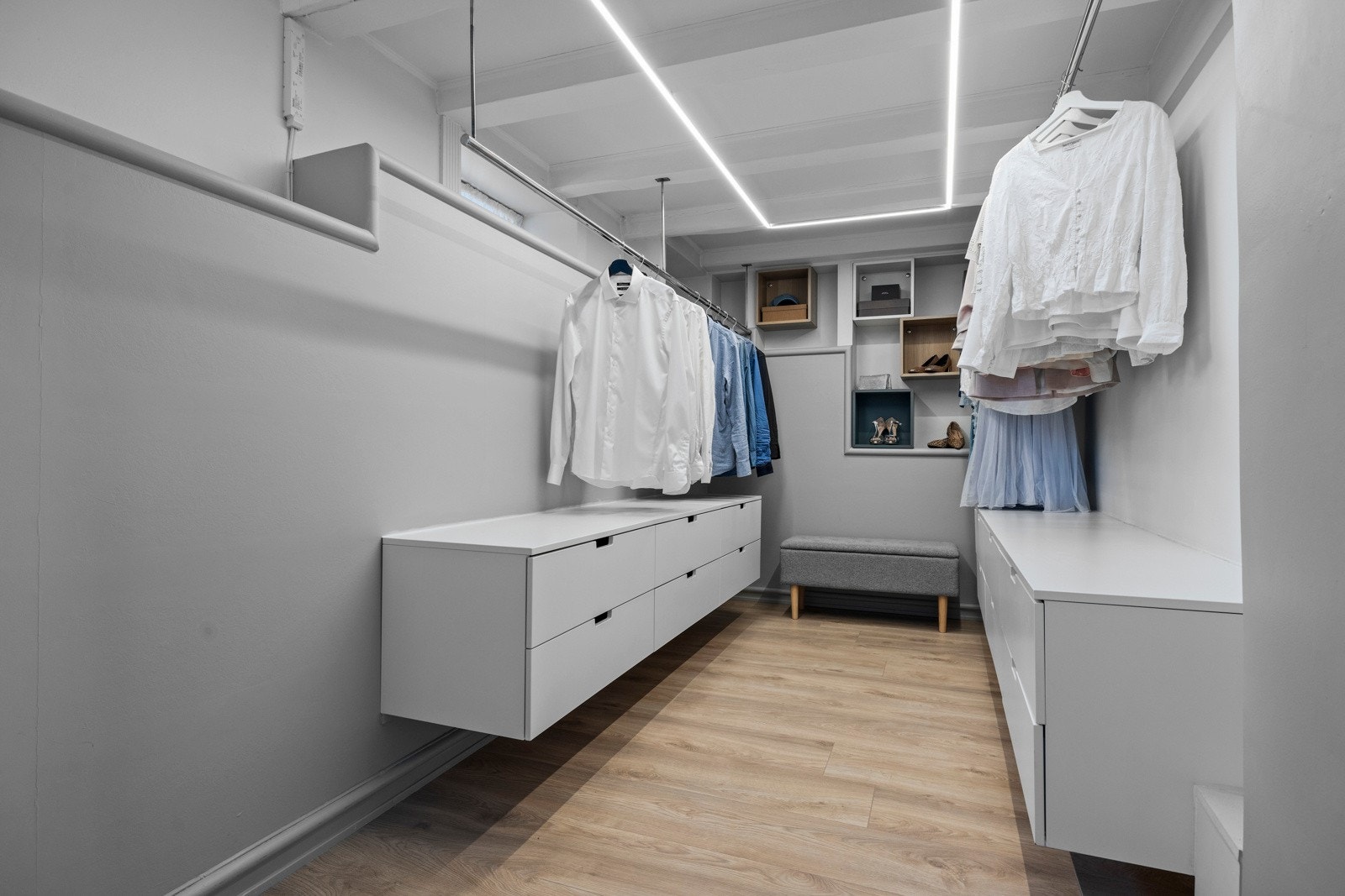 Stor walk-in garderobe med forhøyet himling målt opp til 2,83 meter. Her er det god plass for gode oppbevaringsløsninger i vegghengte skuffeseksjoner og kleshengere på hver side. Galleribilde