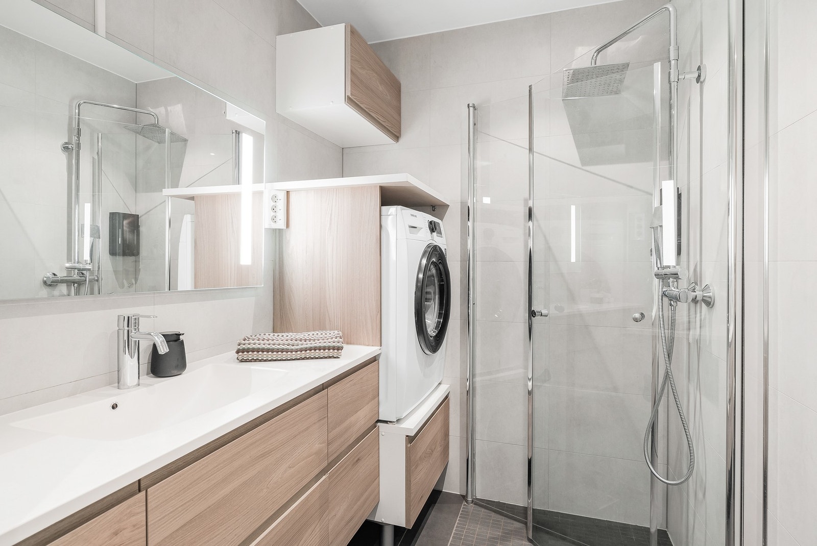 Romslig baderomsinnredning, dusjhjørne og opplegg for vaskemaskin. Gulvvarme. Galleribilde