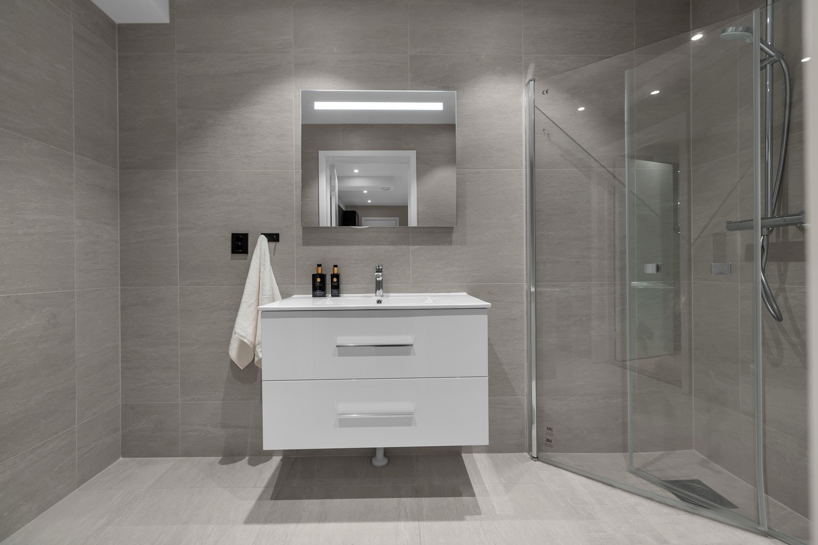 Flislagte gulv og vegger, dusjhjørne, servant med underskap og wc. Galleribilde