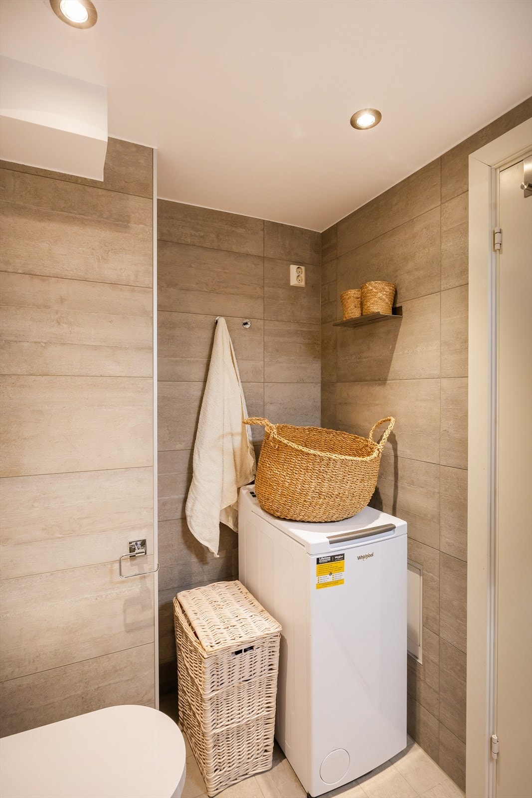 Badet har opplegg for vaskemaskin og store fliser i en delikat farge. Galleribilde