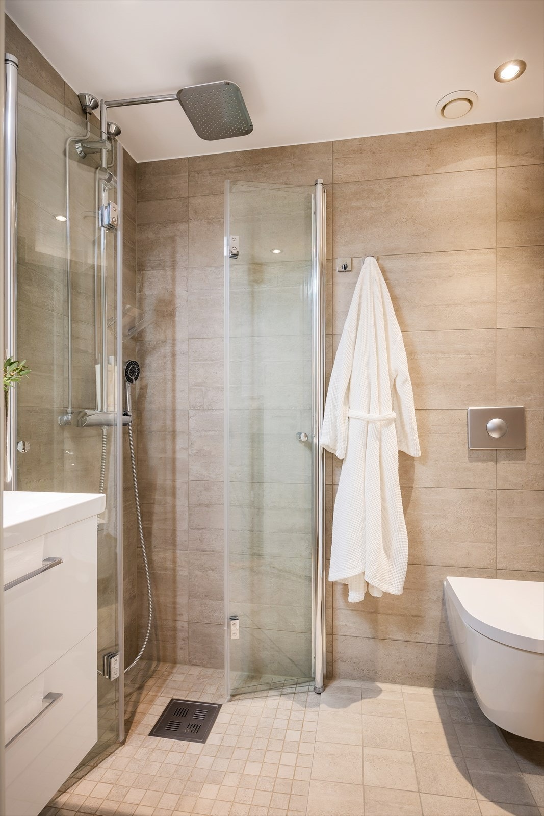 Badet har dusjhjørne med innfellbare dusjdører, servant med under -og overskap, vegghengt wc og opplegg for vaskemaskin. Galleribilde