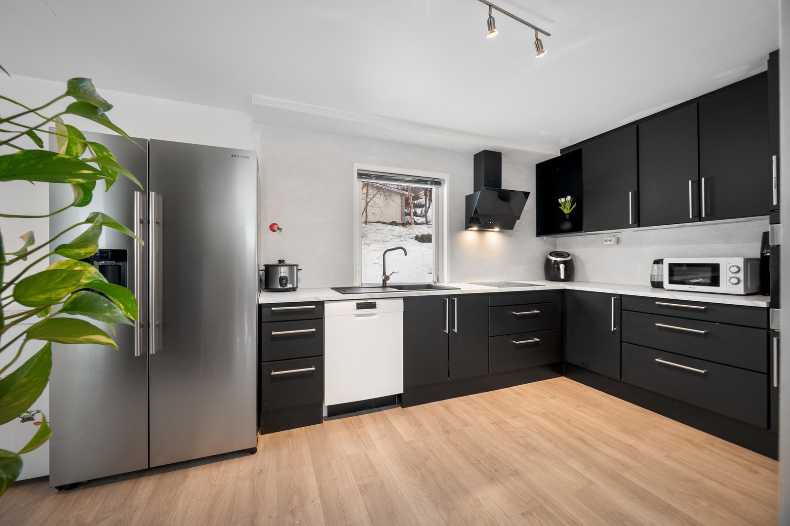 Stilren kjøkkeninnredning med sorte, glatte fronter og benkeplate av laminat Galleribilde