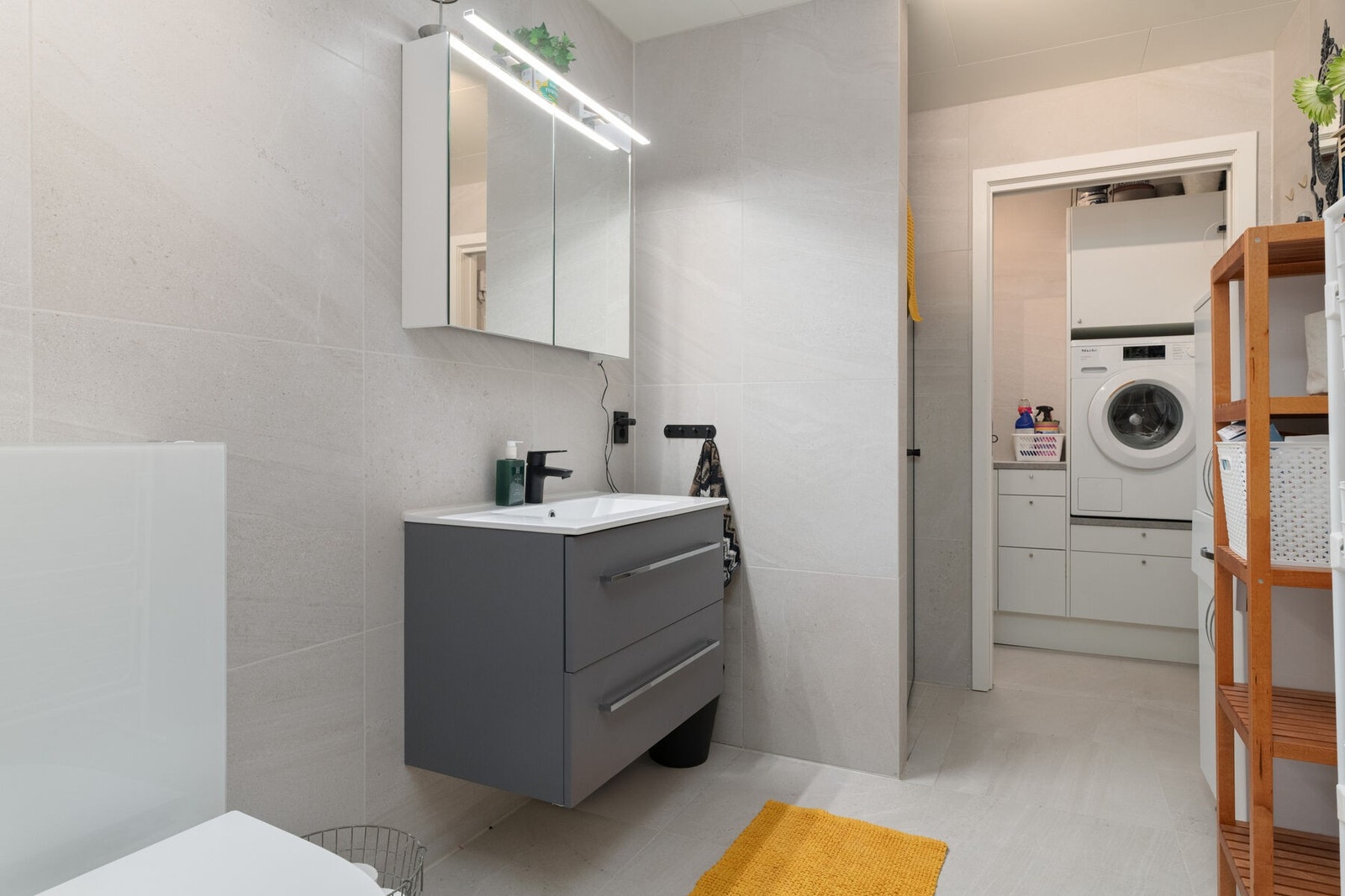 Delikat, flislagt baderom med varmekabler i gulvet. Servant på skuffeseksjon, speilskap, veggmontert wc og dusjnisje. Galleribilde