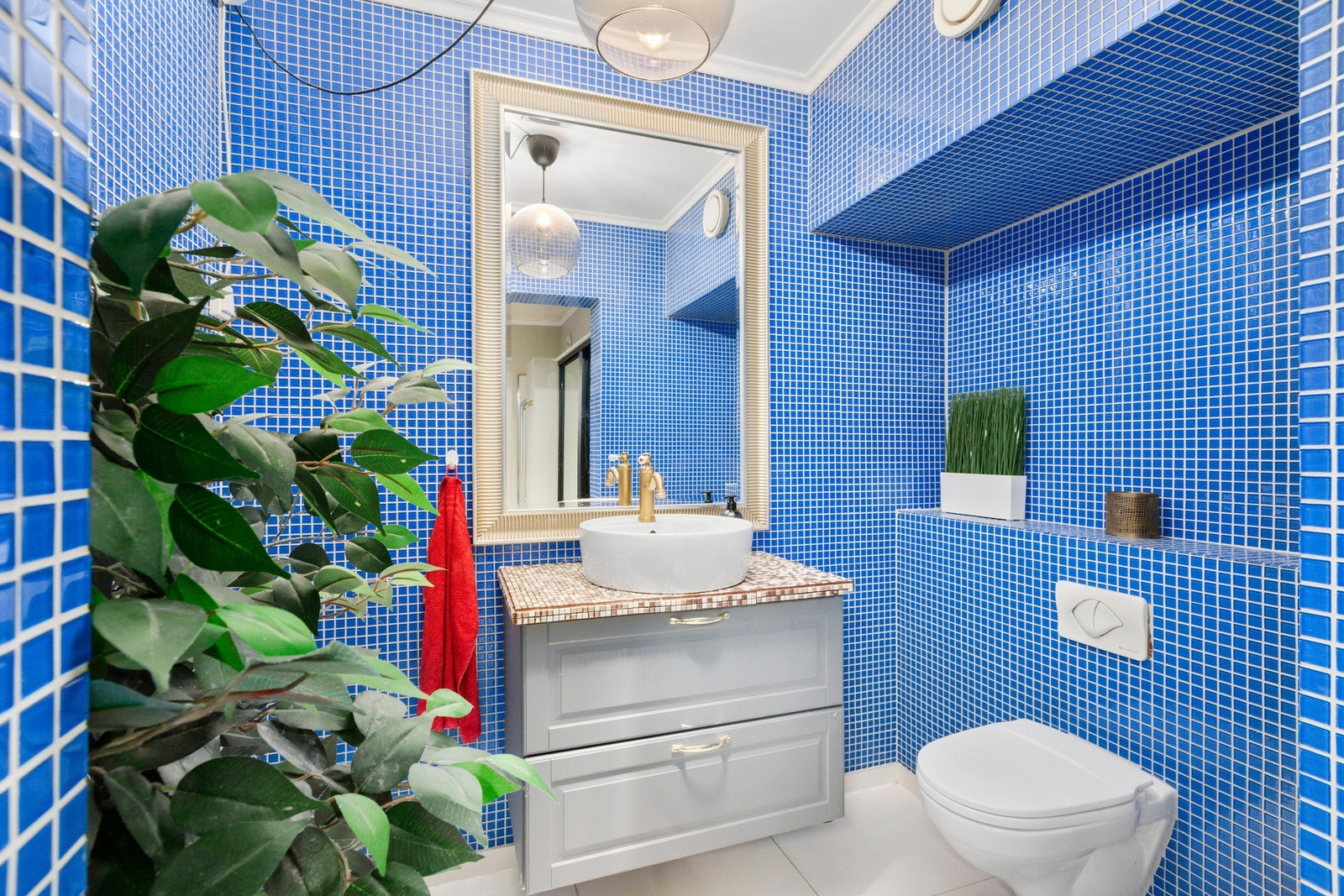 Badet er utstyrt med dusjnisje, veggmontert wc, servantskap og opplegg for vaskemaskin. Galleribilde