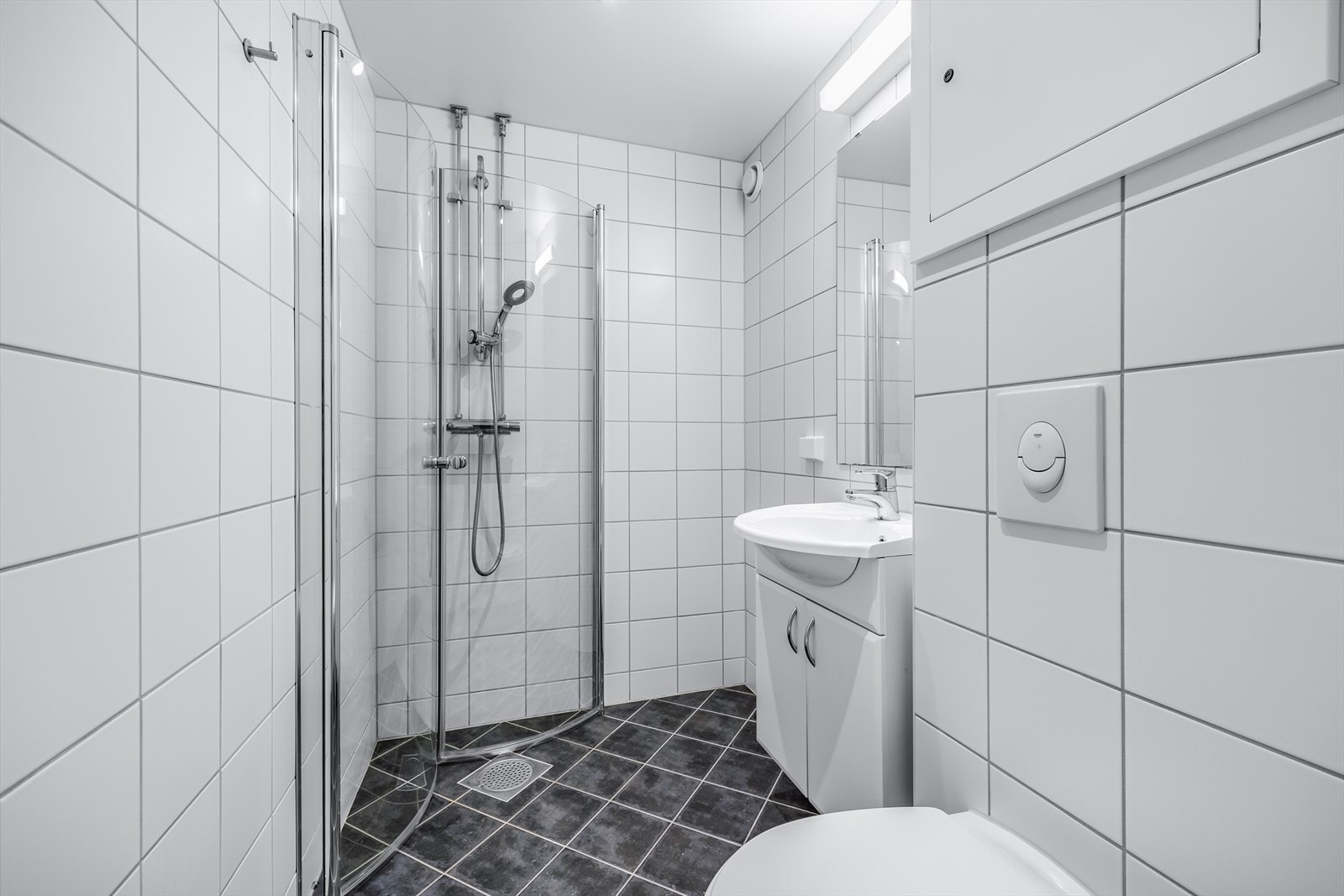 Flislagt baderom med behagelige varmekabler i gulv. Baderommet har lyse fliser på vegg og mørke fliser på gulv. Galleribilde