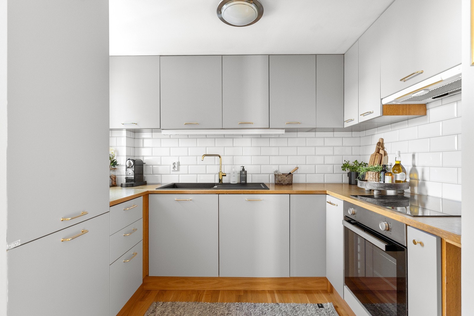 Det er laminat benkeplate med en nedfelt sort komposittvask og ett-greps armatur i gull. Hvitevarer fra Ikea/Whirlpool som oppvaskmaskin, kjøl/frys, stekeovn og platetopp. Galleribilde
