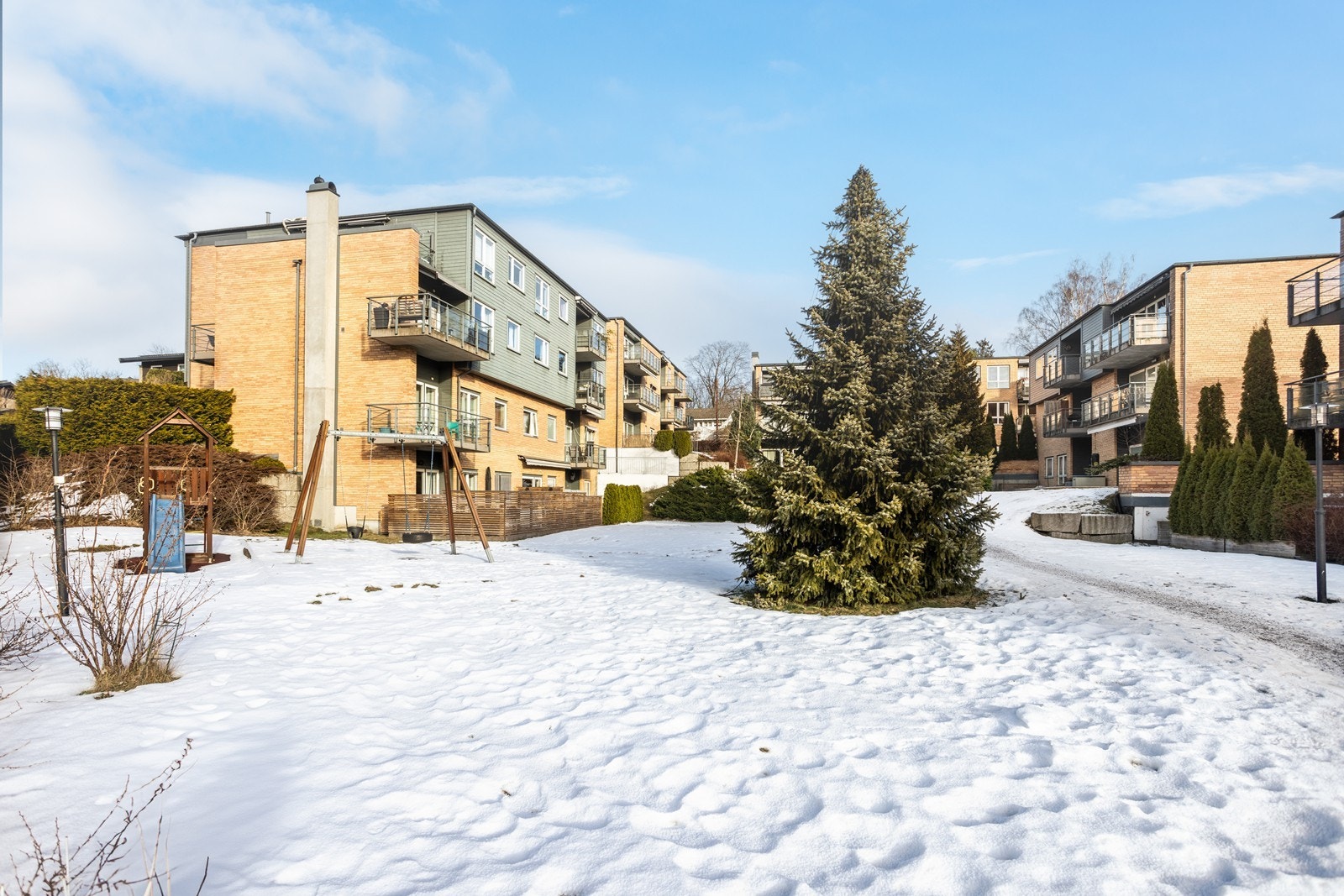 Stort fellesareal med gressplen, sittegrupper, lekeplass m.m. Galleribilde