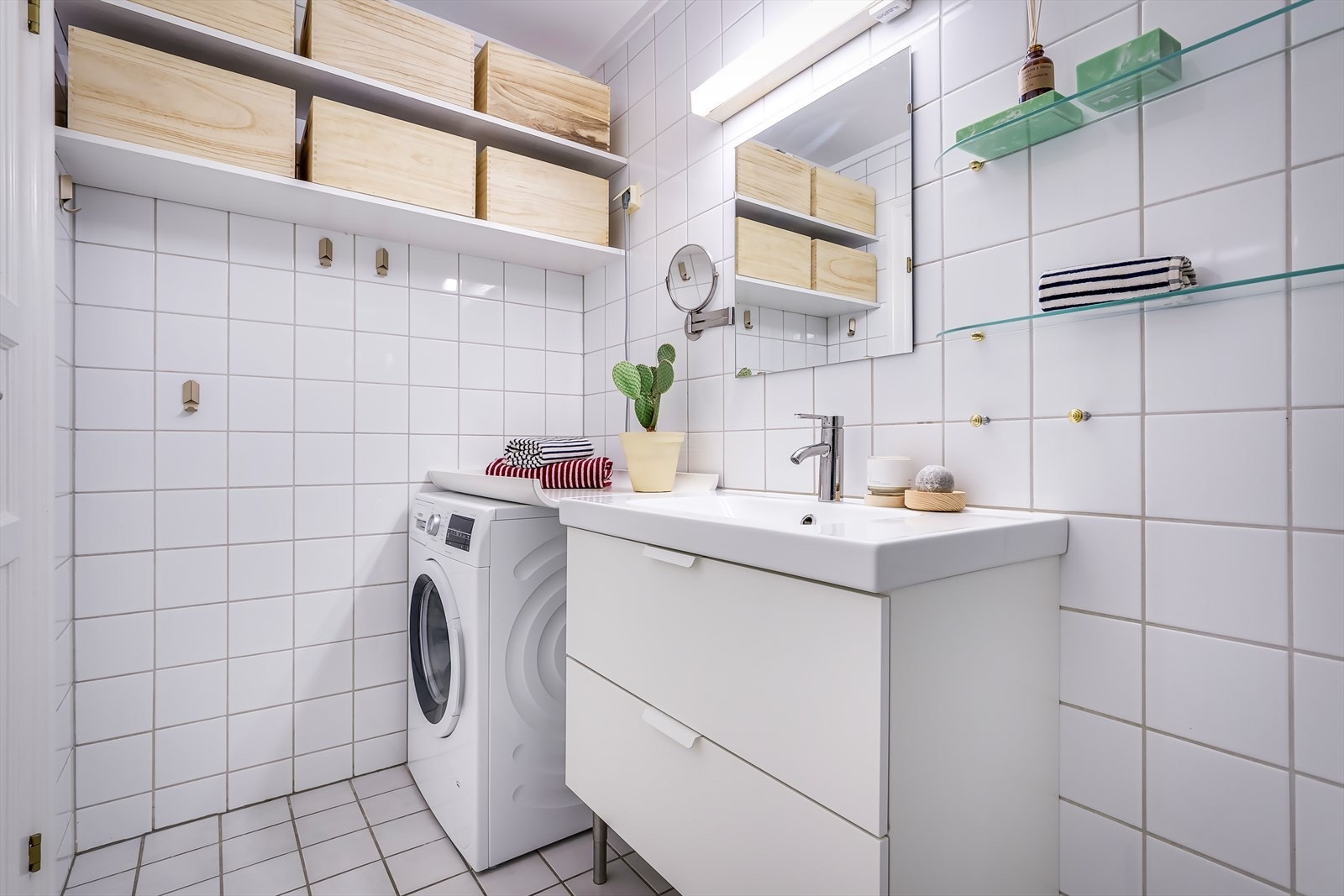 Flislagt bad med opplegg for vaskemaskin og oppbevaring i vegg hengte hyller. Galleribilde