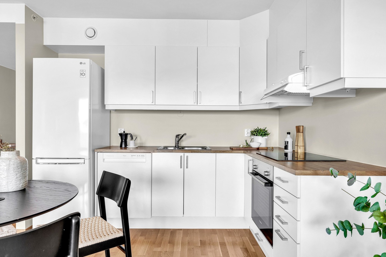 Her får du en lys kjøkkeninnredning med hvite glatte fronter og laminert benkeplate. Galleribilde