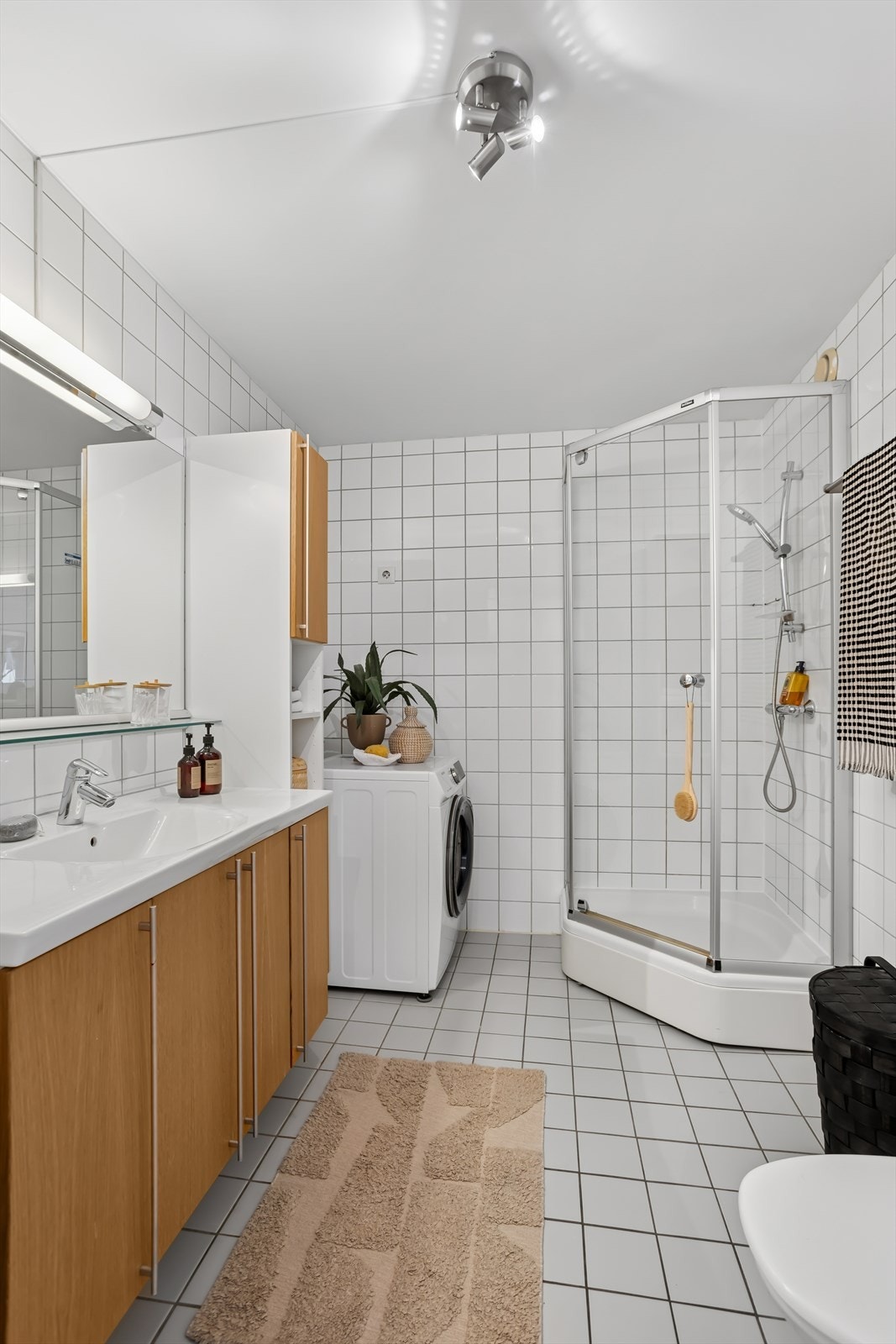 Flislagt baderom med varmekabler i gulvet, opplegg for vaskemaskin og plass til tørketrommel. Galleribilde