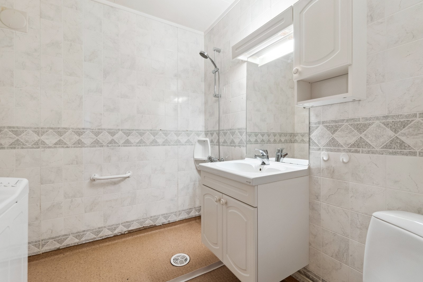 Det neste badet ligger vegg-i-vegg, og har en praktisk beliggenhet i boligen ved en gang som leder til boligens soverom. På dette badet finner du en åpen dusjsone med garnityr på vegg, servantskap og toalett. Galleribilde