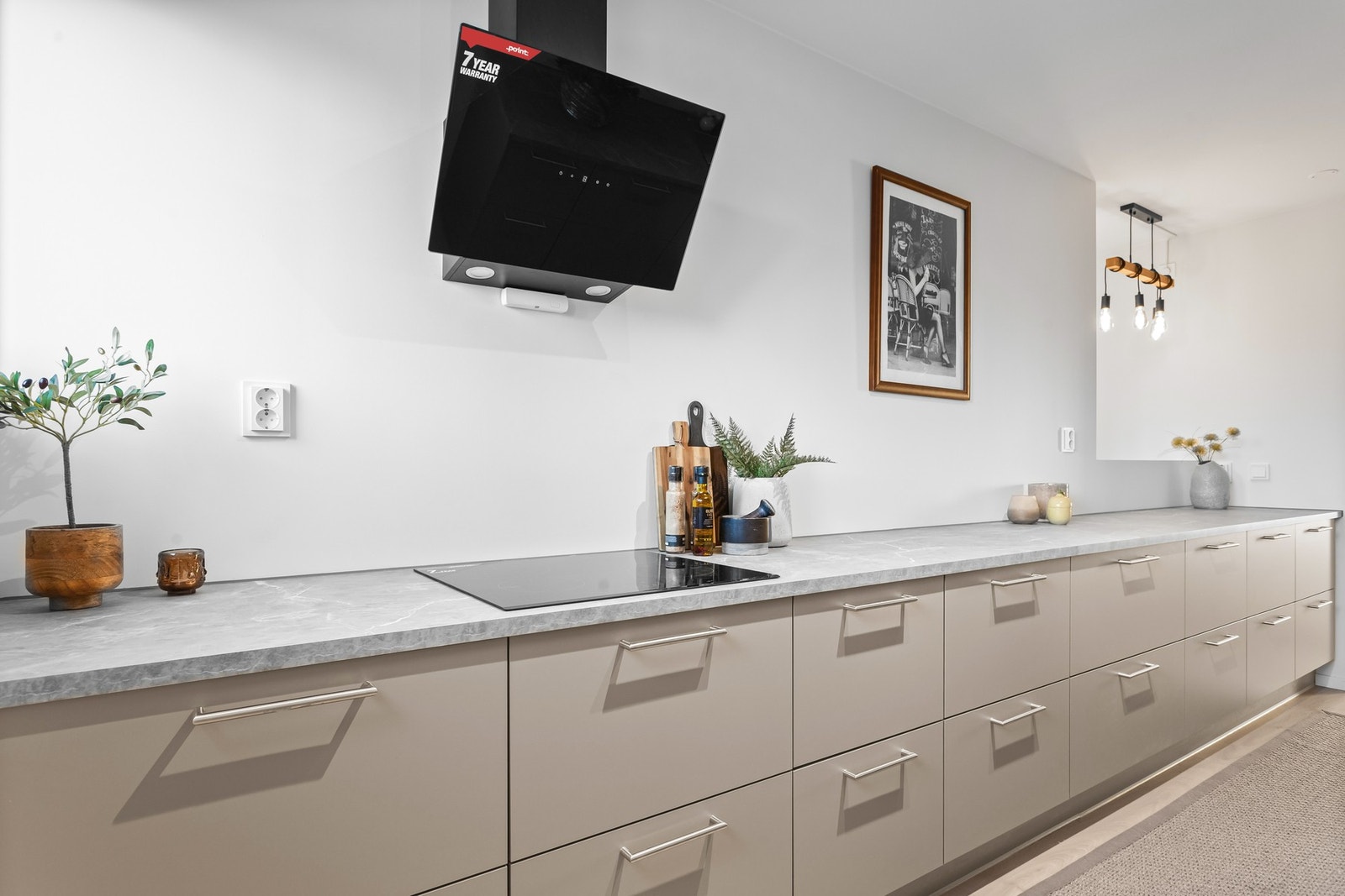 Integrerte hvitevarer i sort som platetopp, mikro, stekeovn, oppvaskmaskin, kjøl/fryseskap samt ventilator over stekesone Galleribilde