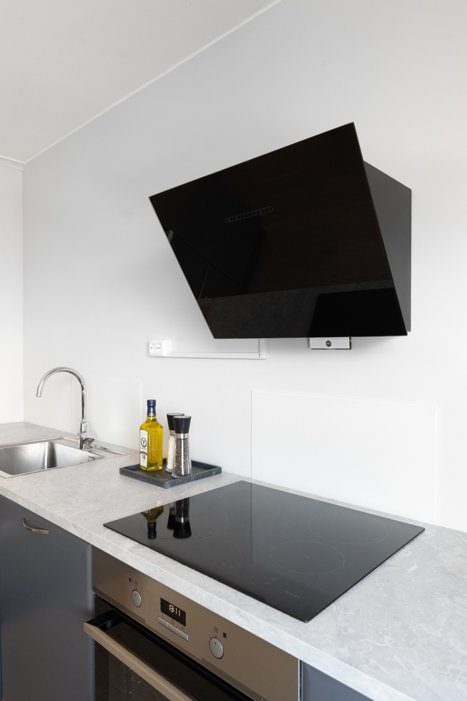 Glassplate på vegg bak vask og koketopp. Integrert stekeovn, oppvaskmaskin, kjøleskap og induksjonstopp. Galleribilde