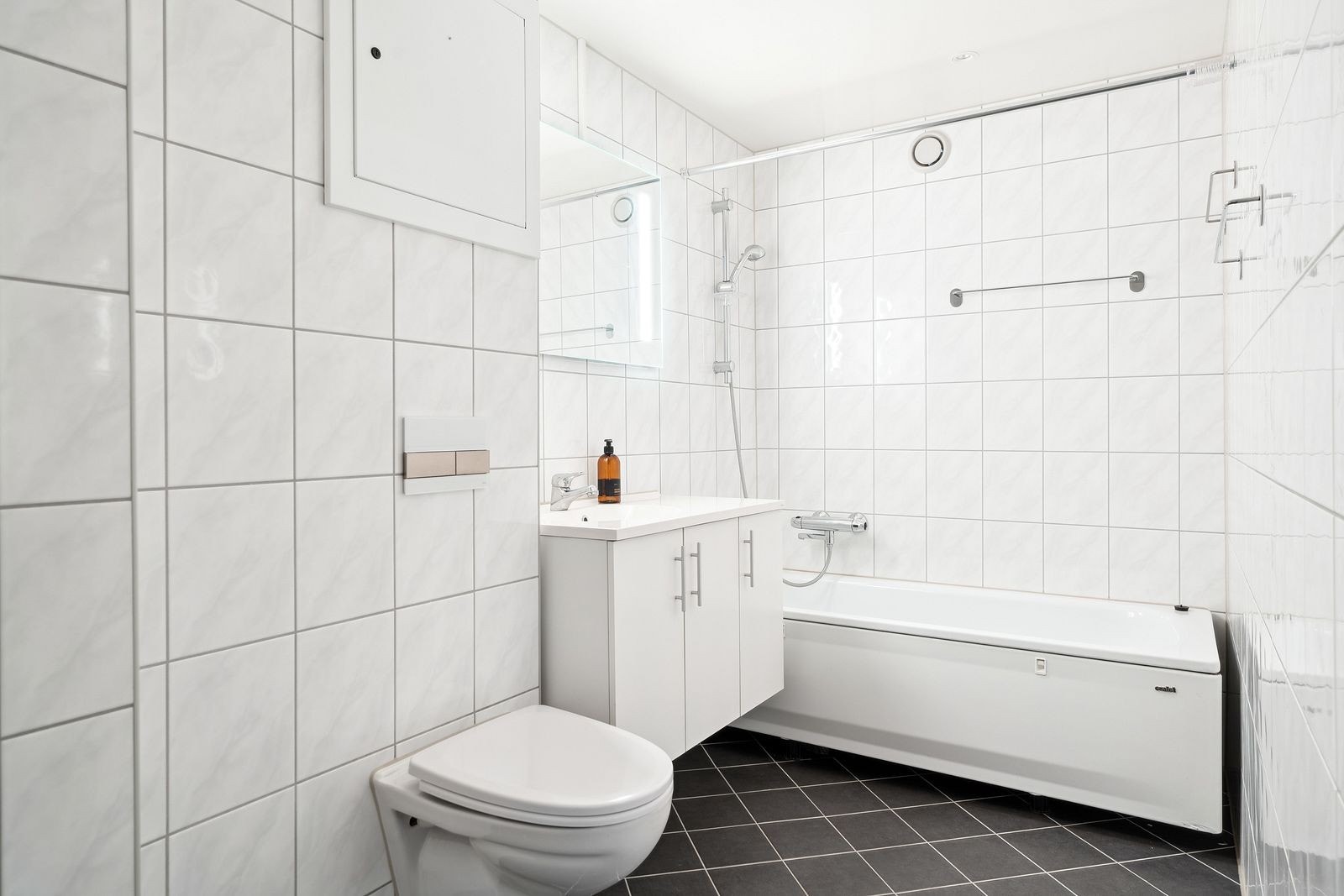 Pent flislagt bad med varme i gulv, vegghengt wc og badekar/dusj. Galleribilde