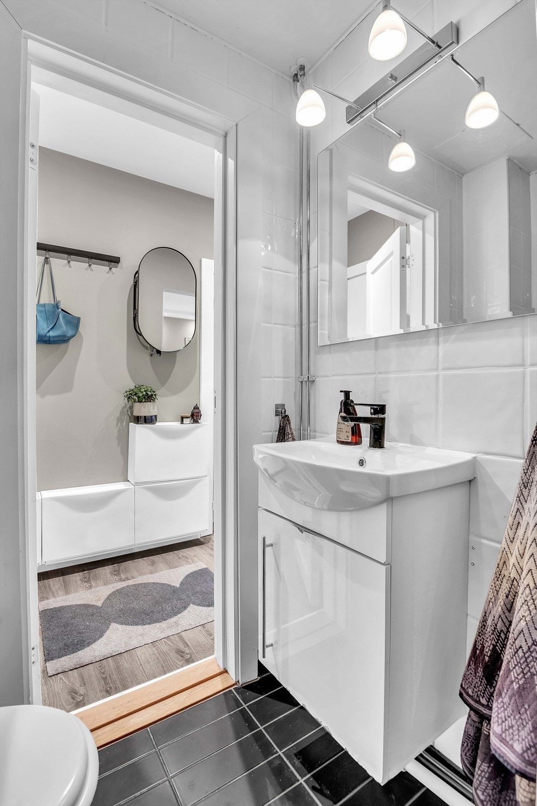 Baderomsinnredning med flislagt gulv med varme og flislagte vegger, himling av malt flate, vegghengt servantskap med glatt front og heldekkende servant med ett-greps armatur. Galleribilde