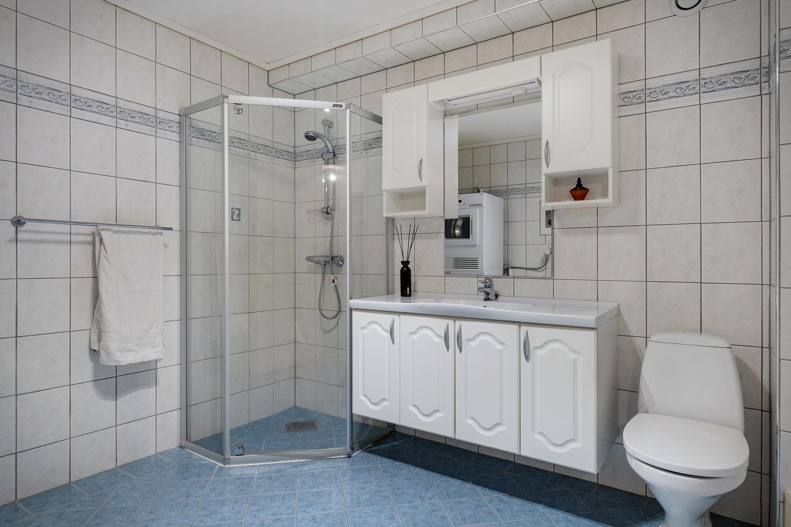 Helfliset baderom innredet med dusjhjørne, toalett og servant med møblement, speil og belysning. Galleribilde