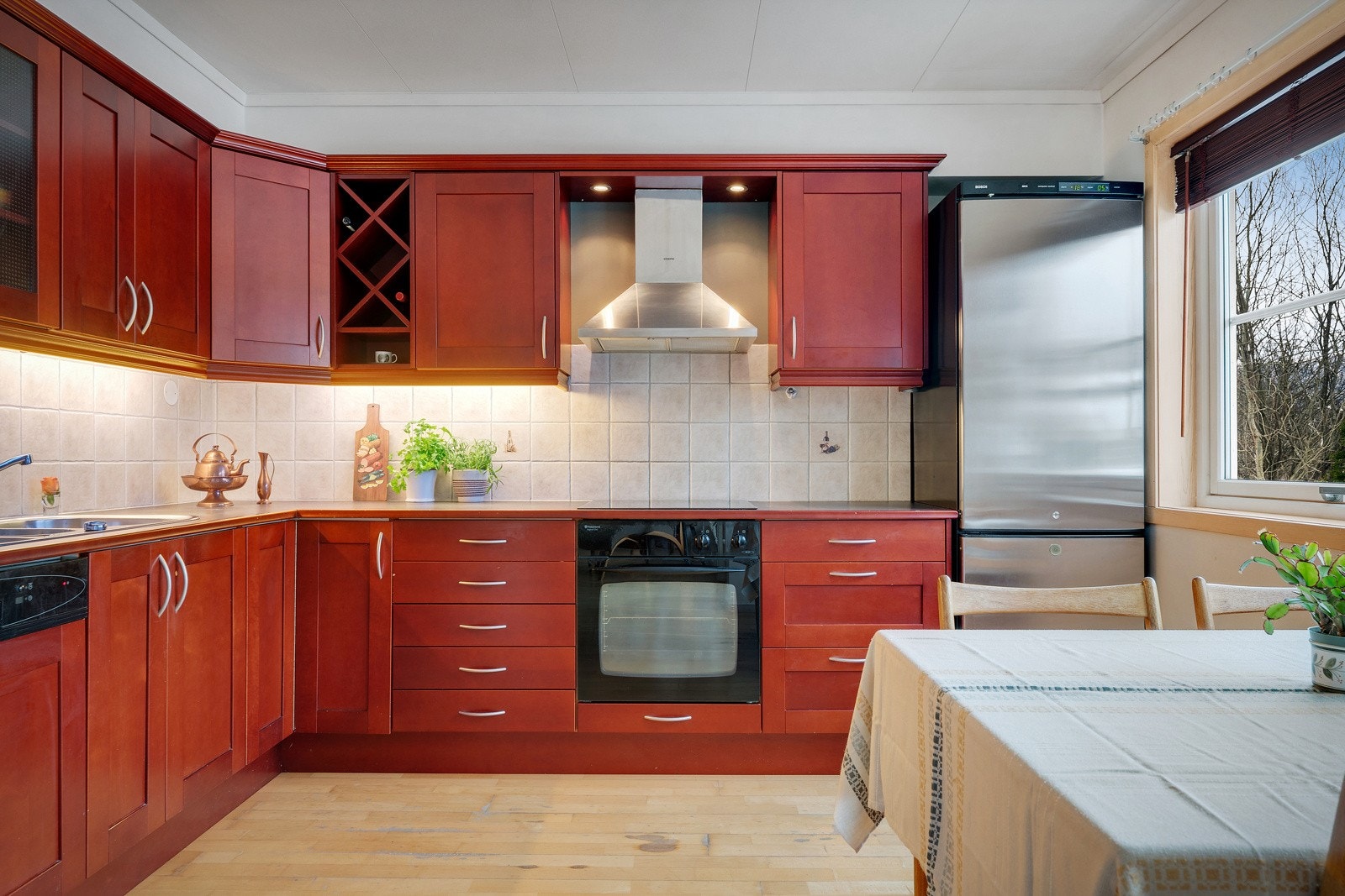 Kjøkkeninnredning med profilerte fornter i mørk rødtone og benkeplate i laminat. Galleribilde