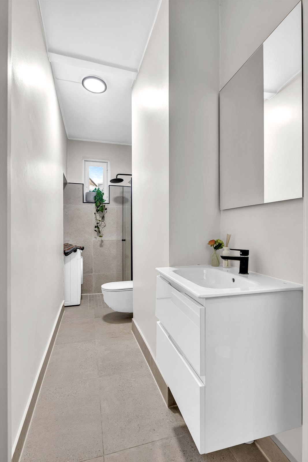 Badet ble totalrenovert av firma i 2022. Fliser på gulv og i dusjsone, varmekabler i gulvet, vegghengt toalett samt servant med underskap Galleribilde