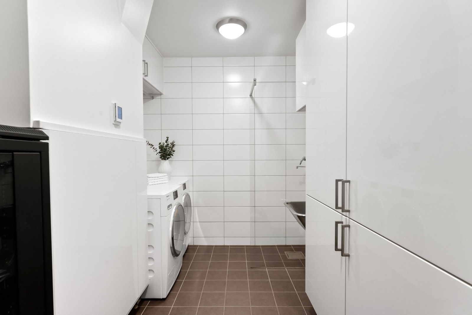 Vaskerommet har adkomst via skyvedør direkte fra hallen. Nisje med opplegg for vaskemaskin og tørketrommel samt dusjnisje og vask på andre siden. Galleribilde