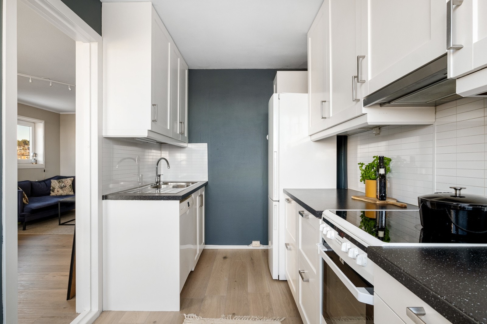 Et hyggelig og funksjonelt kjøkken med innredning langs to vegger med lyse, profilerte fronter og laminat benkeplate med dobbel kum. Galleribilde